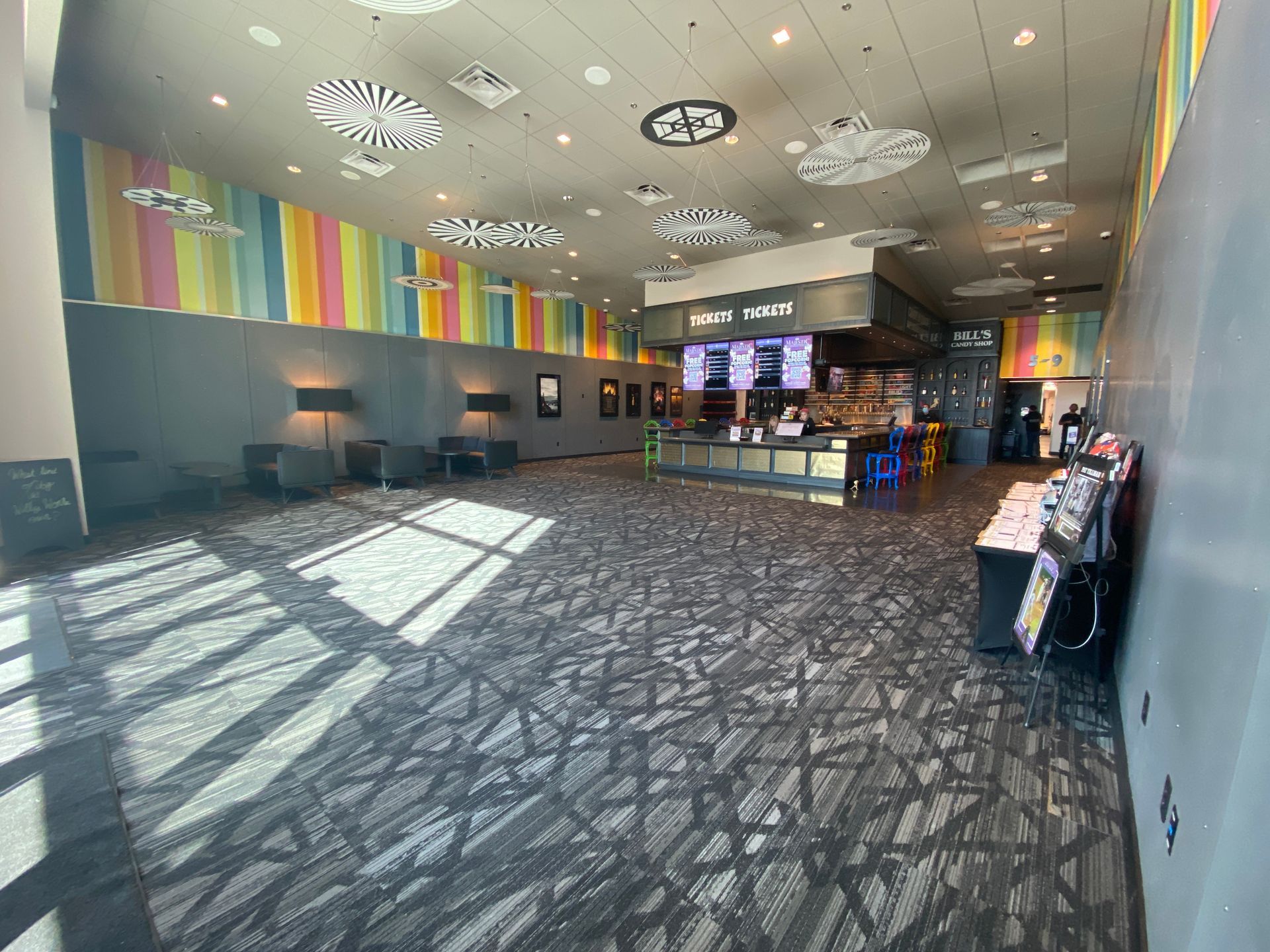 Movie theater lobby with a concession stand, colorful wall, and patterned carpet.