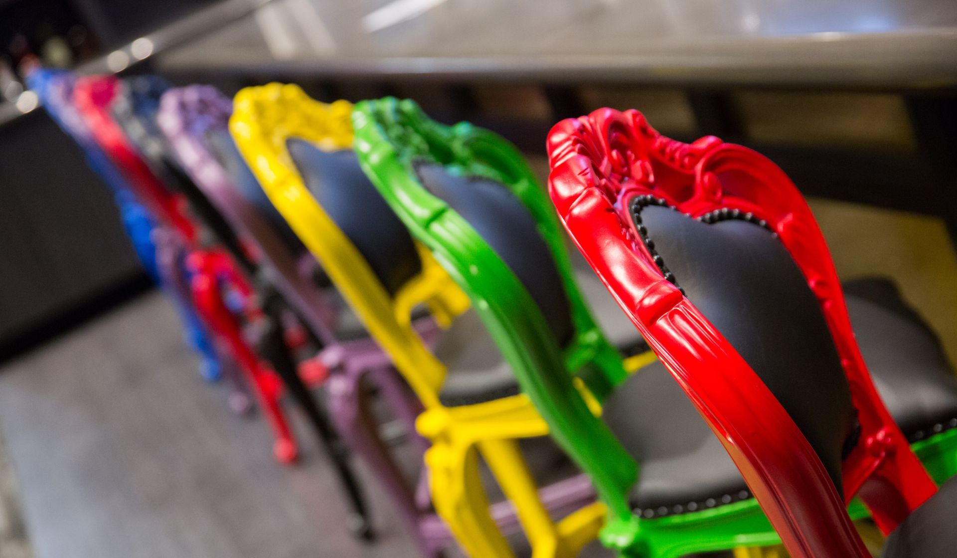 Row of colorful, ornate chairs; red, blue, purple, yellow, green.