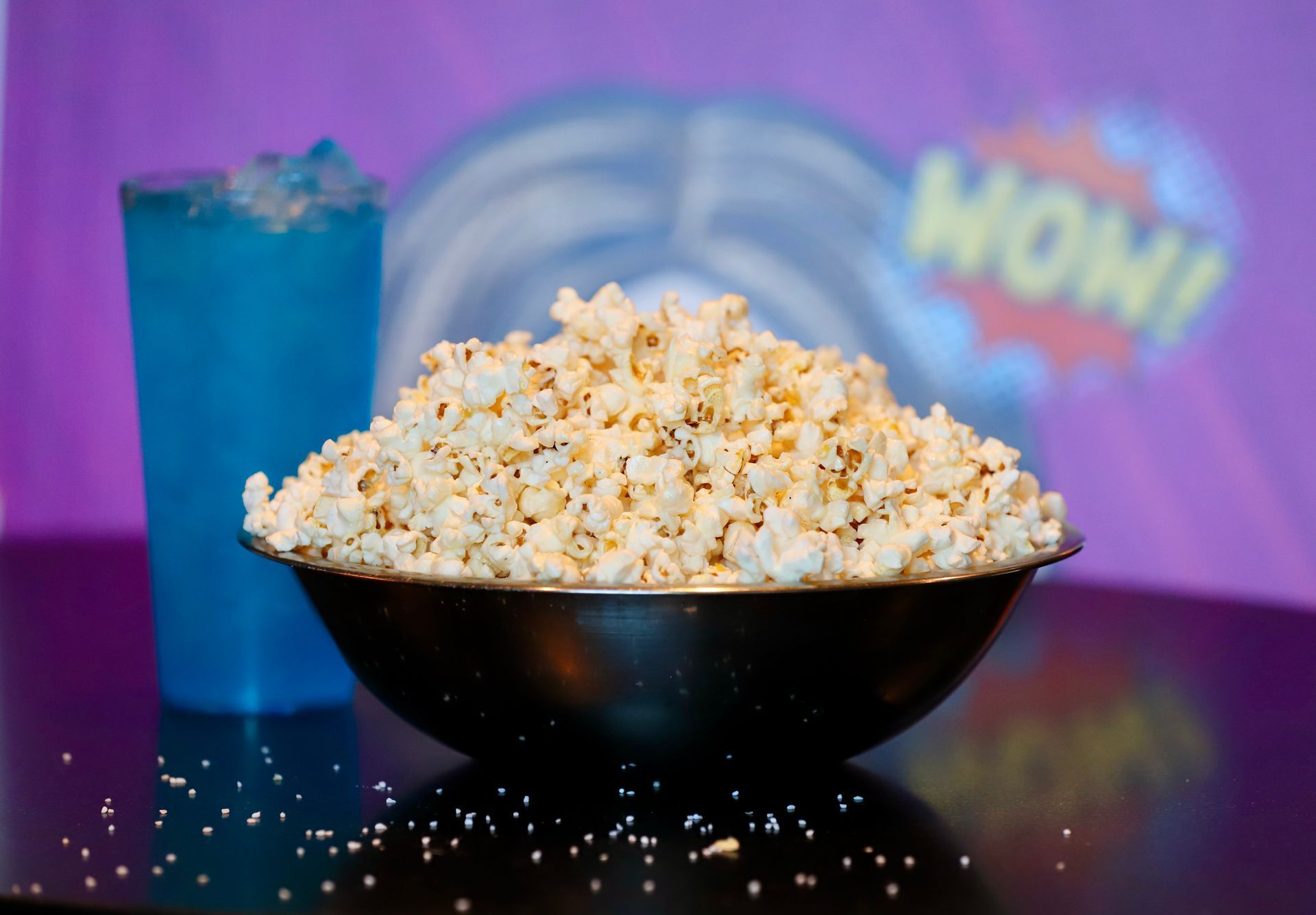 Large bowl of popcorn, blue drink, and a WOW! backdrop.