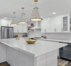 A kitchen with white cabinets and a large island with a bowl of food on it.