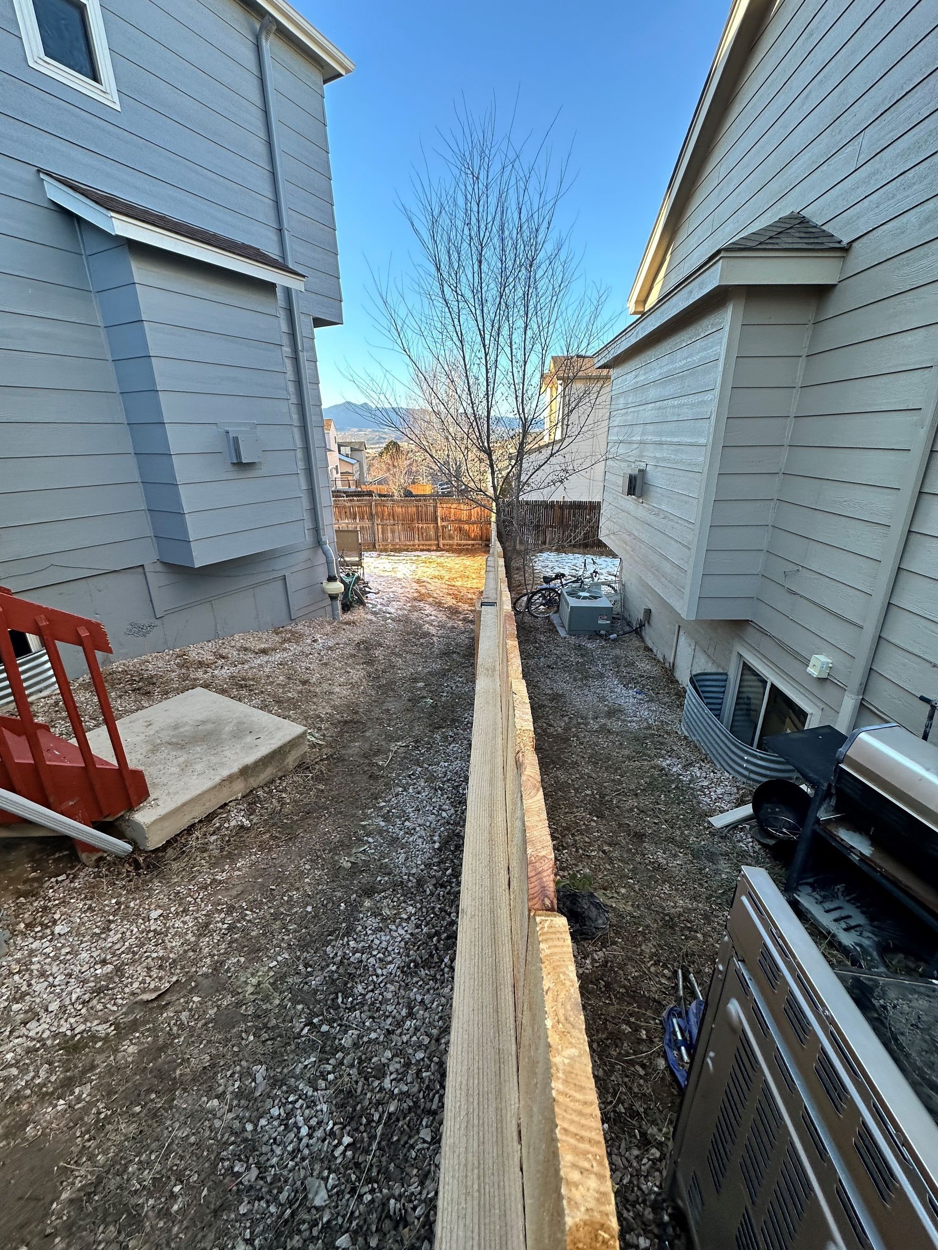 A wooden fence is being built between two houses.
