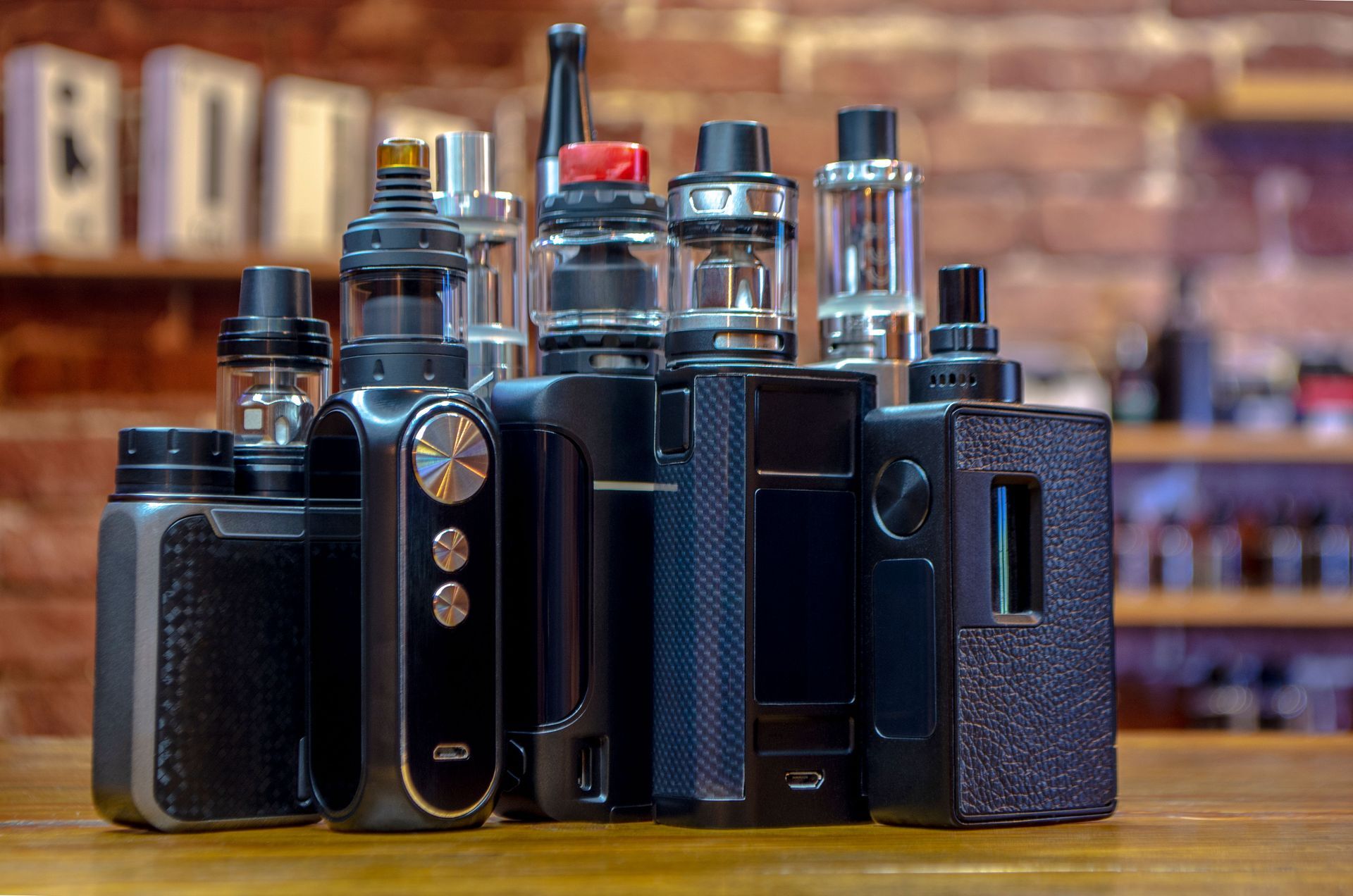 A bunch of electronic cigarettes are sitting on a wooden table.