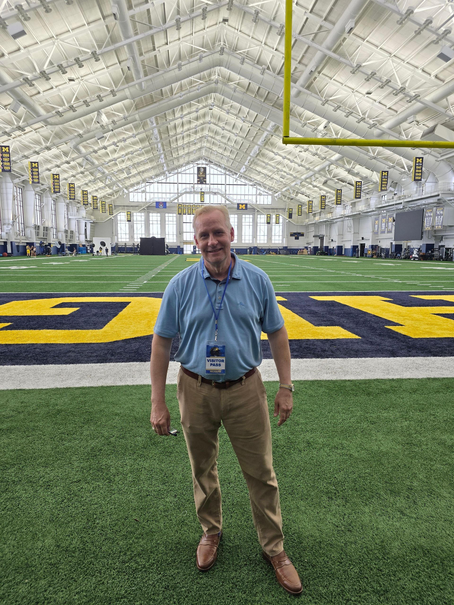 A man is standing in the middle of a football field.