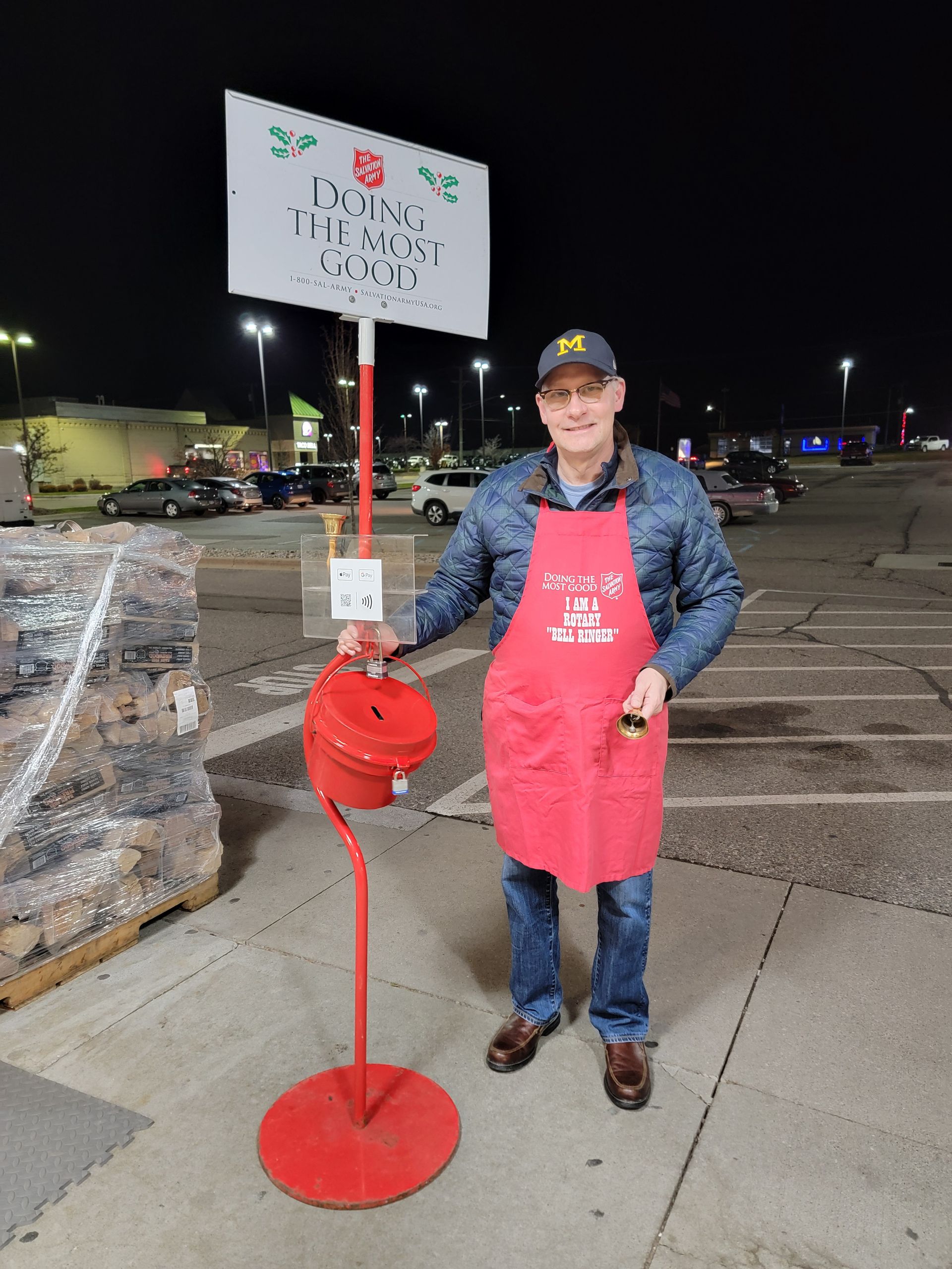 A man in a red apron is standing in front of a sign that says ducks unlimited