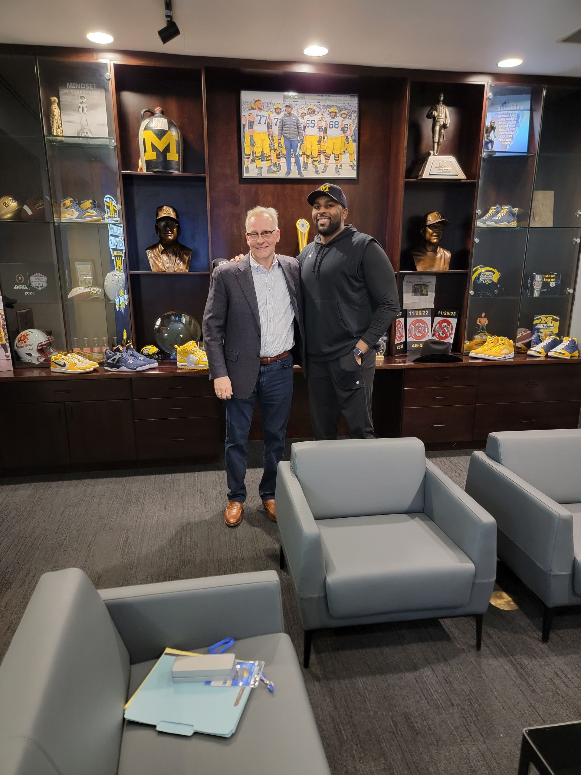 Two men are posing for a picture in a living room.