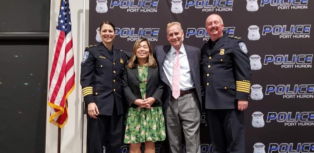 A group of police officers are posing for a picture in front of an american flag.