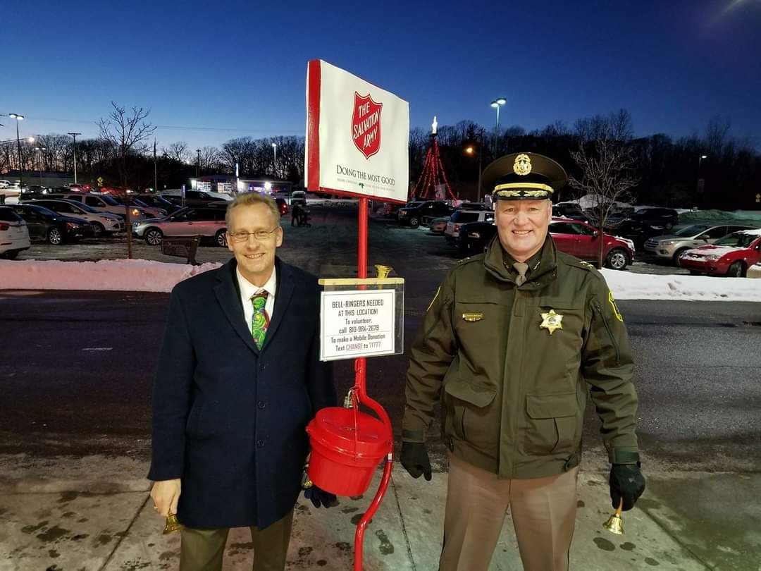 Two men are standing next to each other in a parking lot.