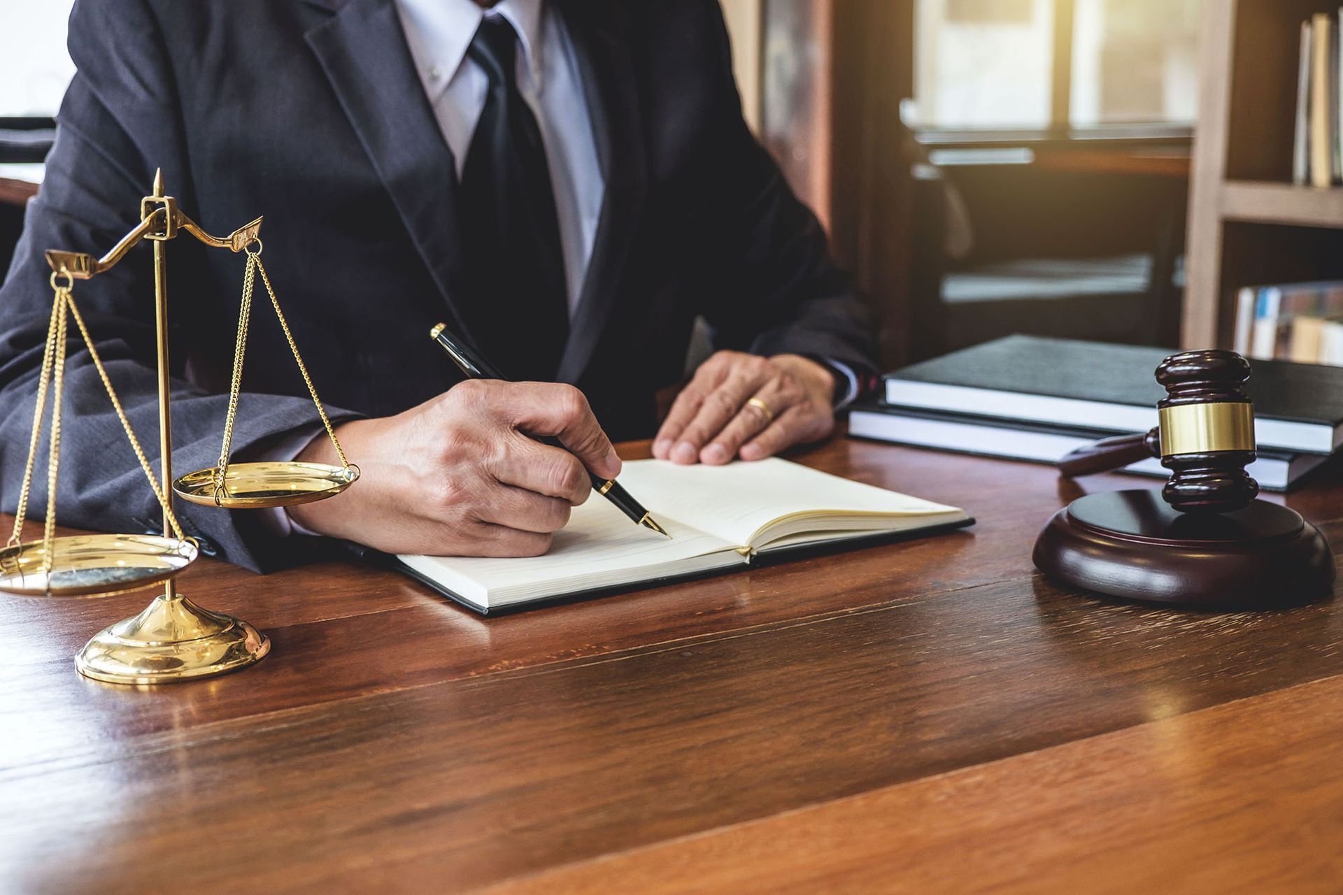 A lawyer is sitting at a desk writing in a notebook.