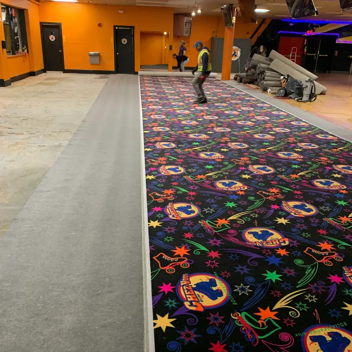 Roller rink interior with new carpet. Person on roller skates on the carpet, orange walls.
