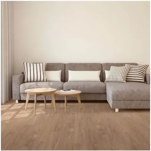 A modern living room with a gray sectional sofa, two round wooden coffee tables, and hardwood flooring.
