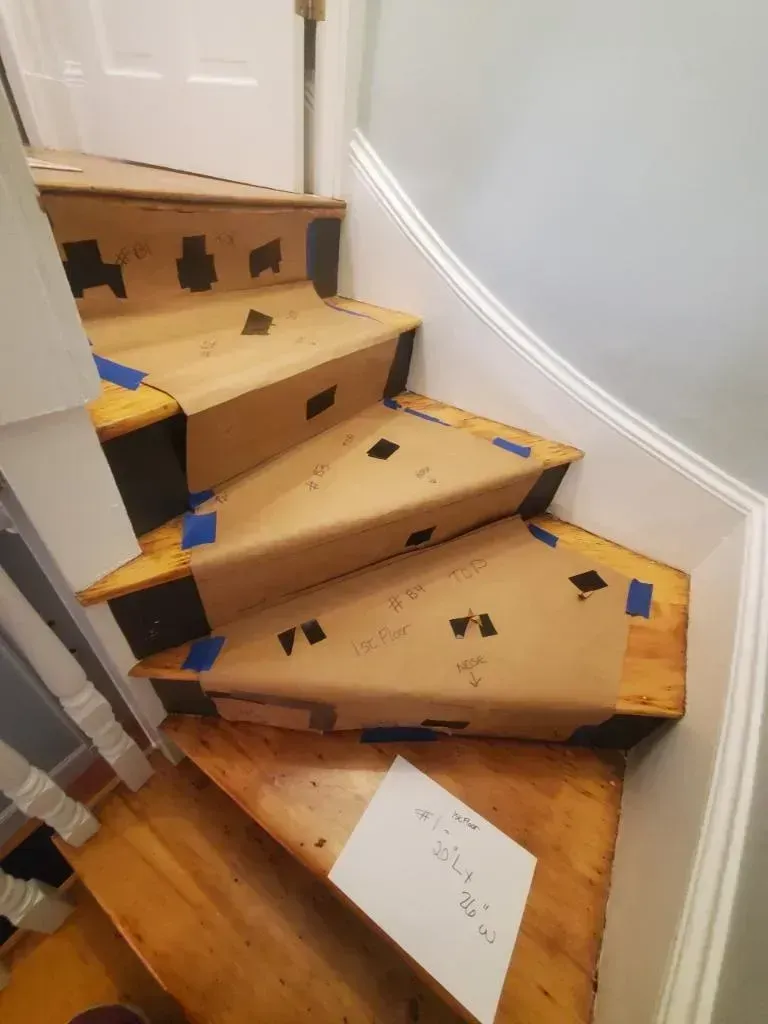 Wooden staircase partially covered with cardboard for protection during a renovation.