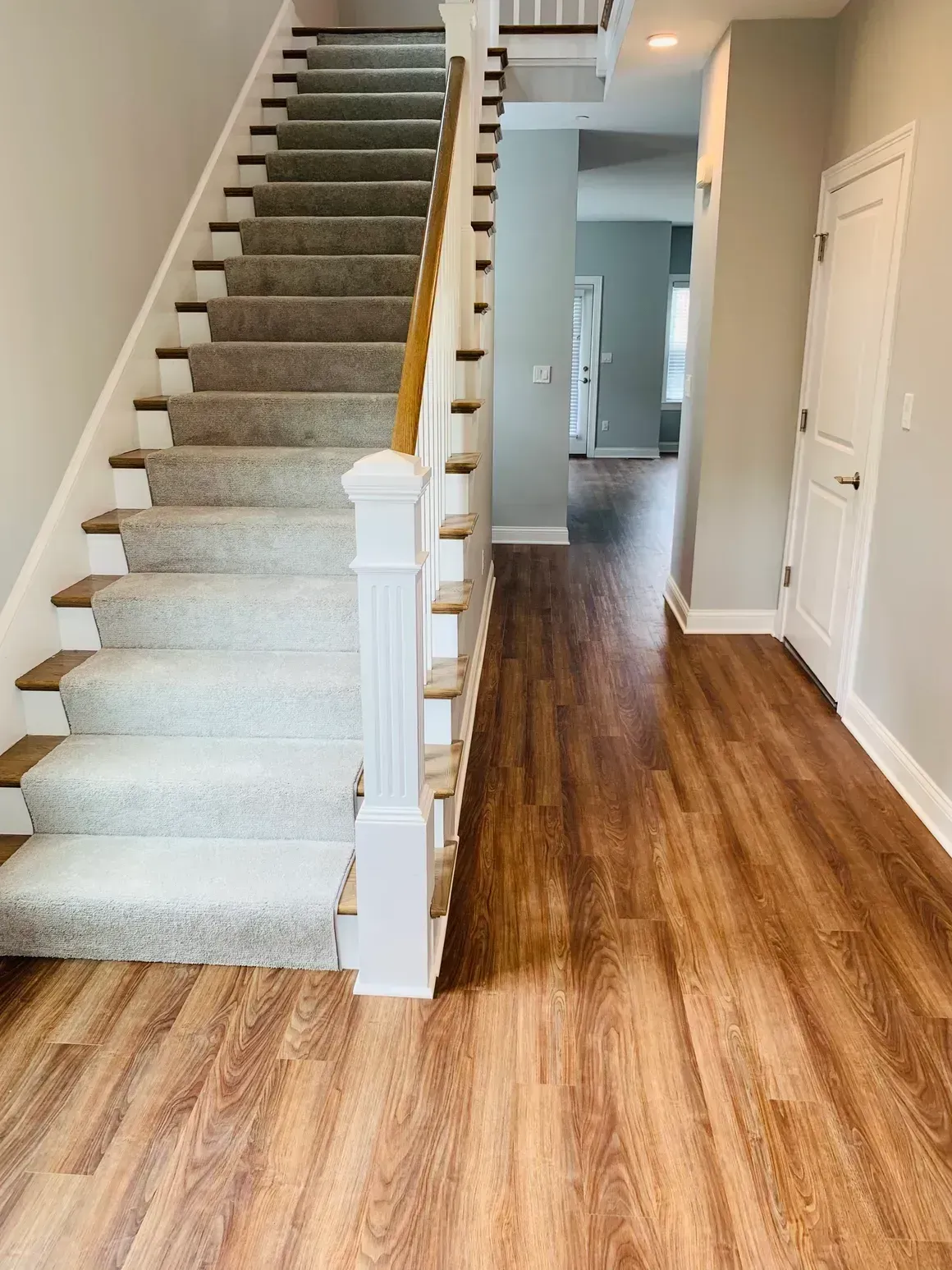 Entryway with stairs, carpeted treads, wood floors, and white trim.