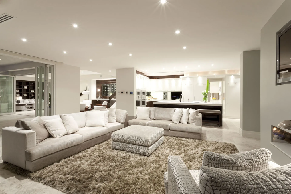 Modern living room with neutral colors, large sofas, and a shaggy rug.
