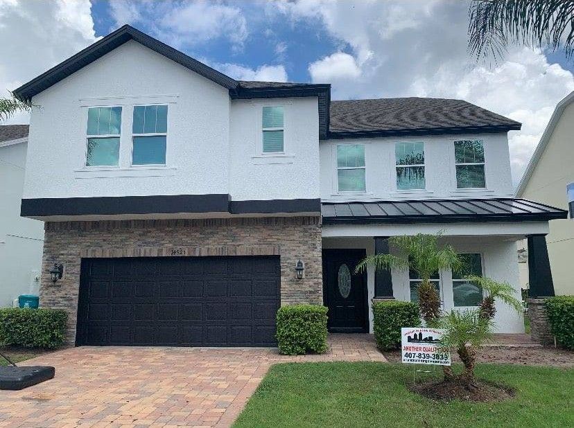 A large white house with a black garage door is for sale.