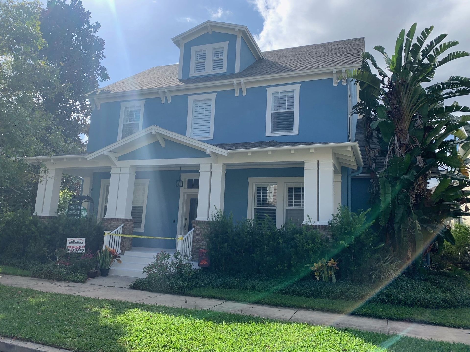 A blue house with white trim and a porch on a sunny day.