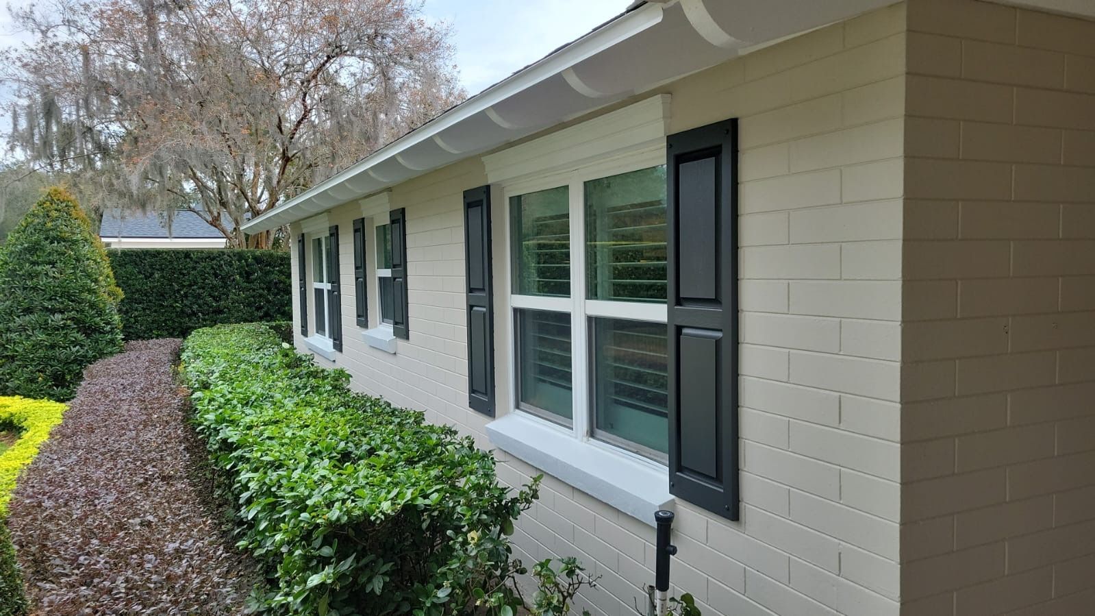 A white brick house with black shutters on the windows