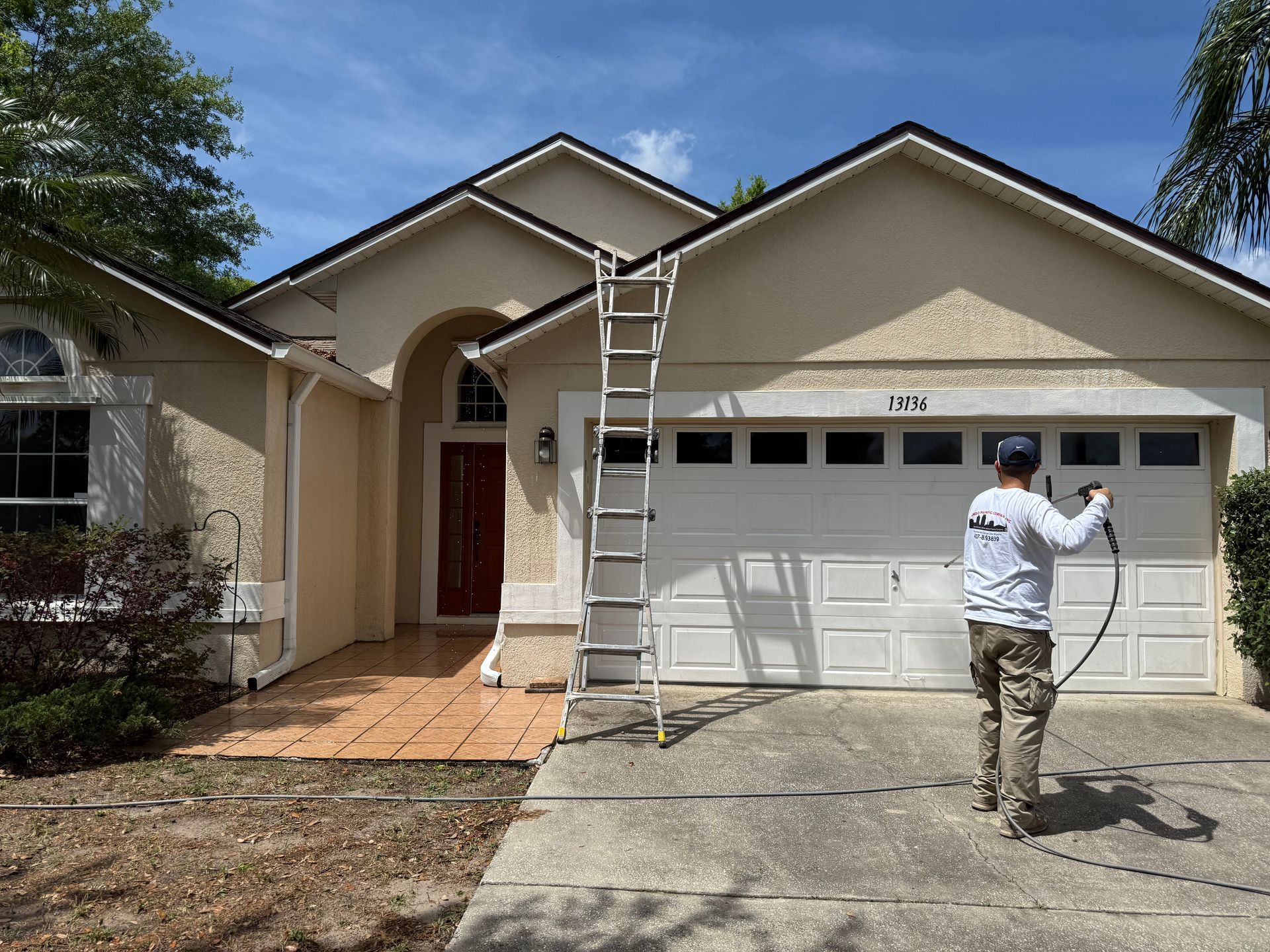 A man is cleaning the front of a house with a hose.