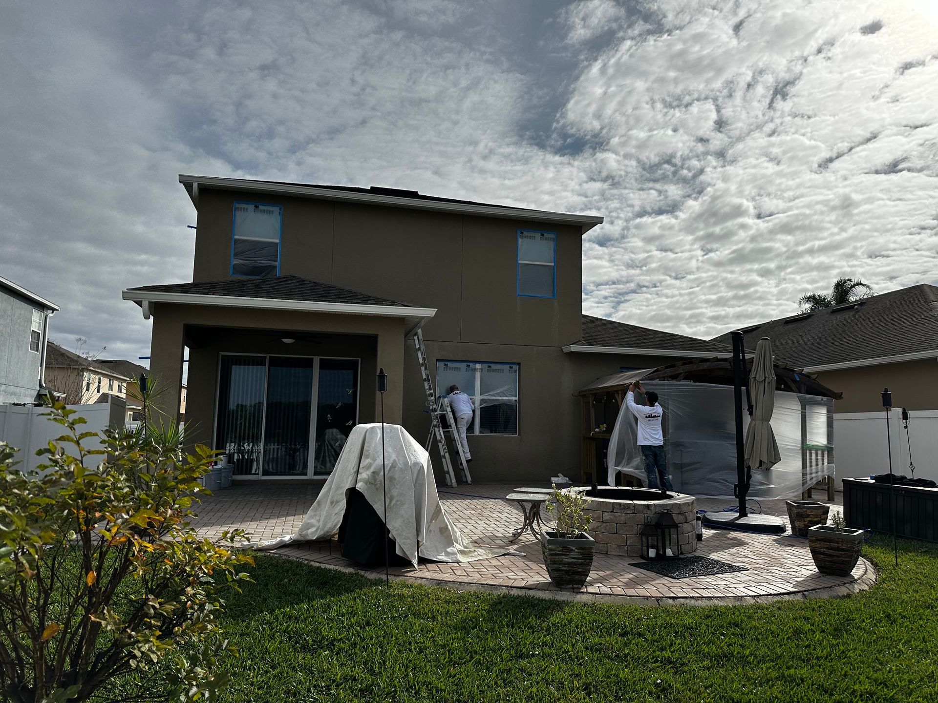 A man is standing in front of a house, painting it.