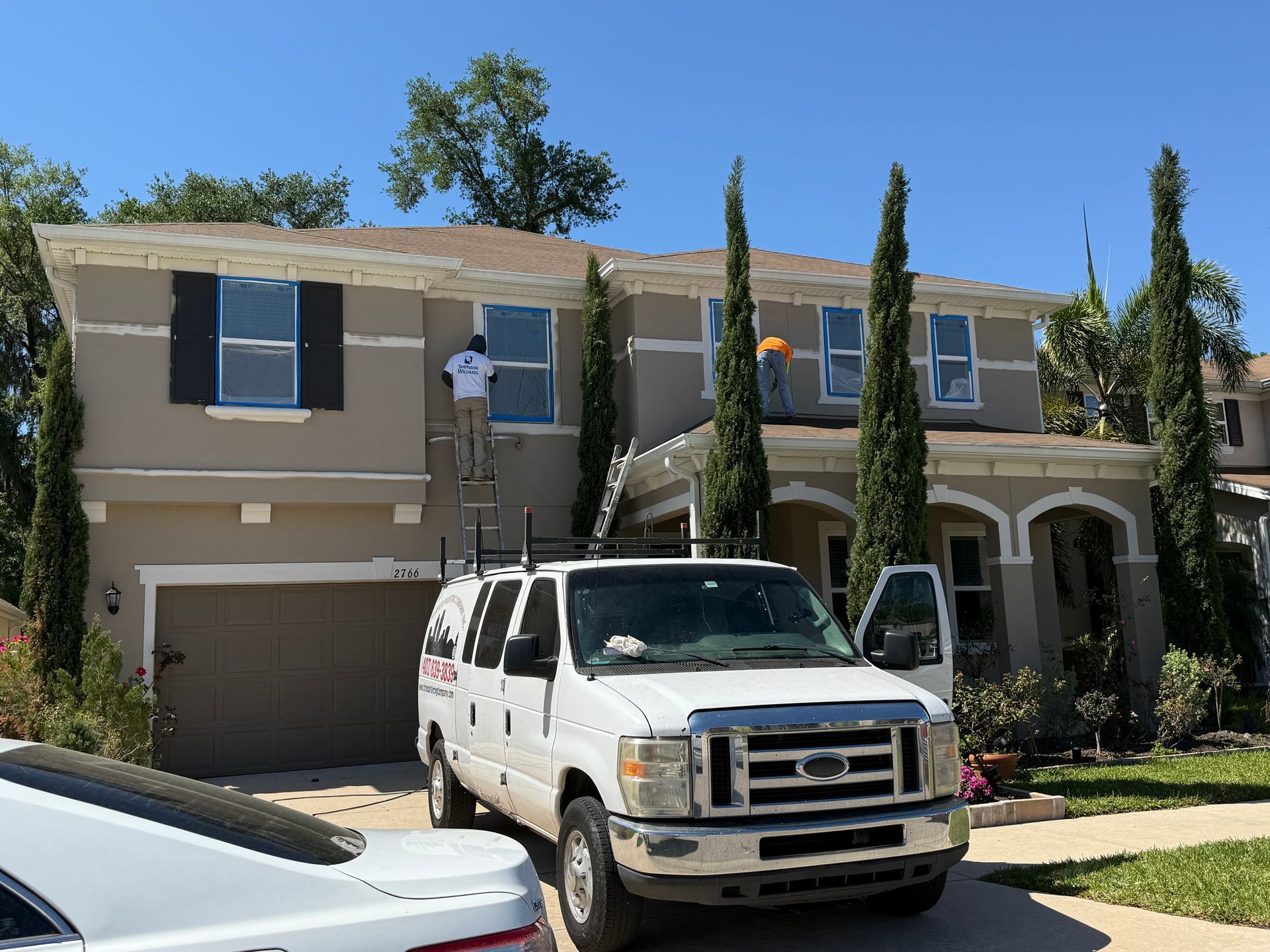 A white van is parked in front of a house being painted.