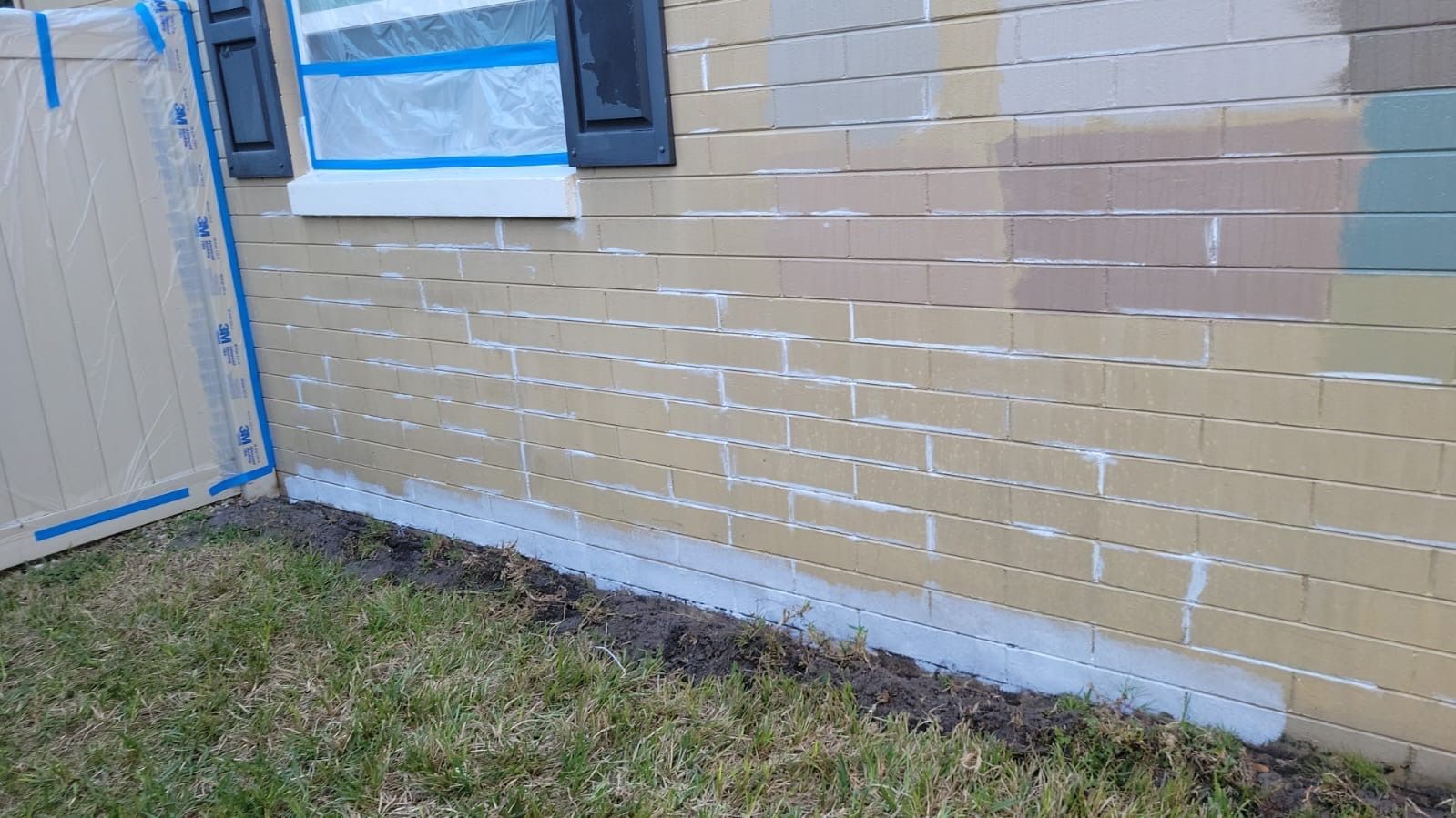 A brick wall is being painted white.