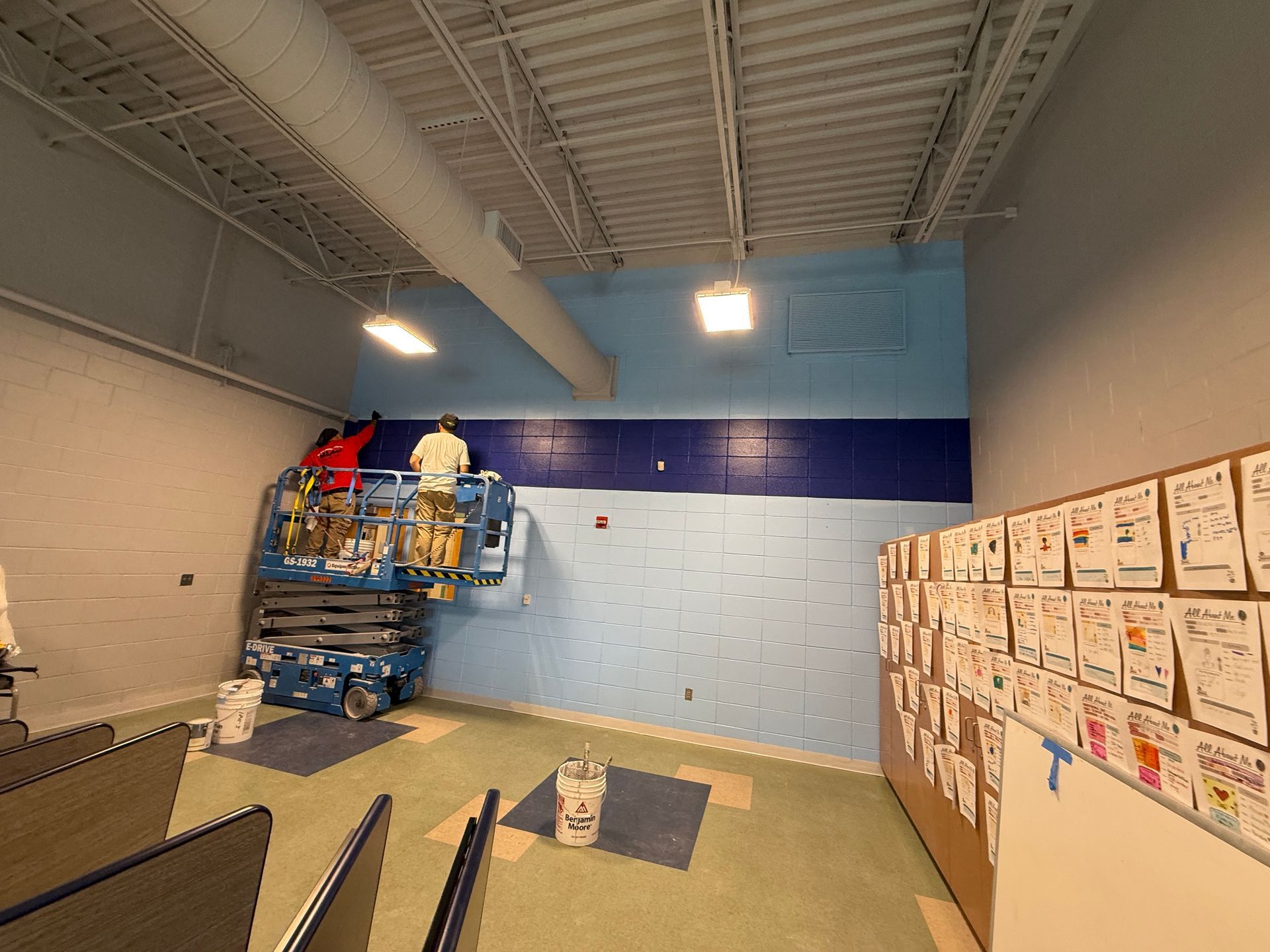 A group of people are painting a wall in a room.