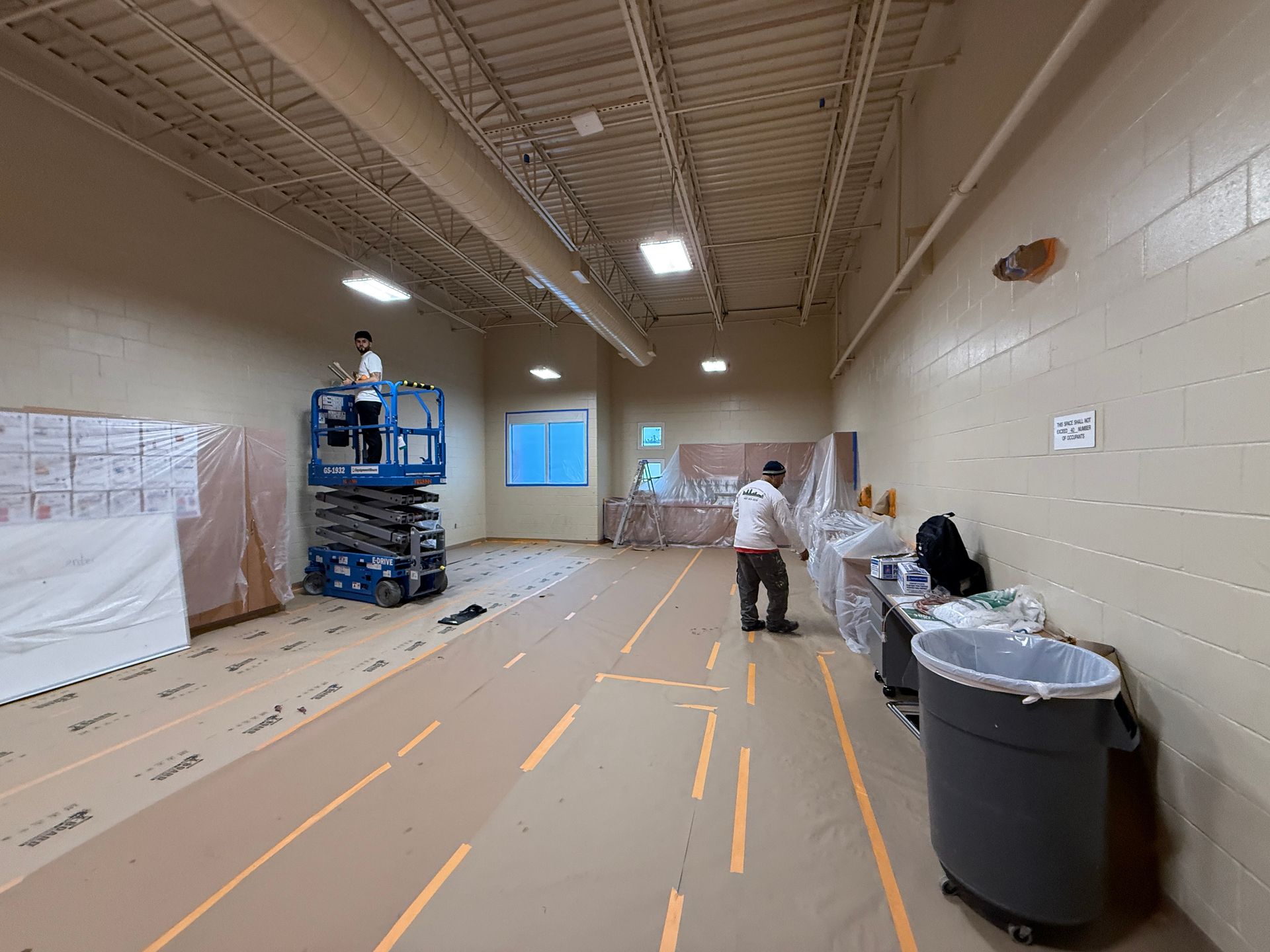 A man is painting a wall in a large room.