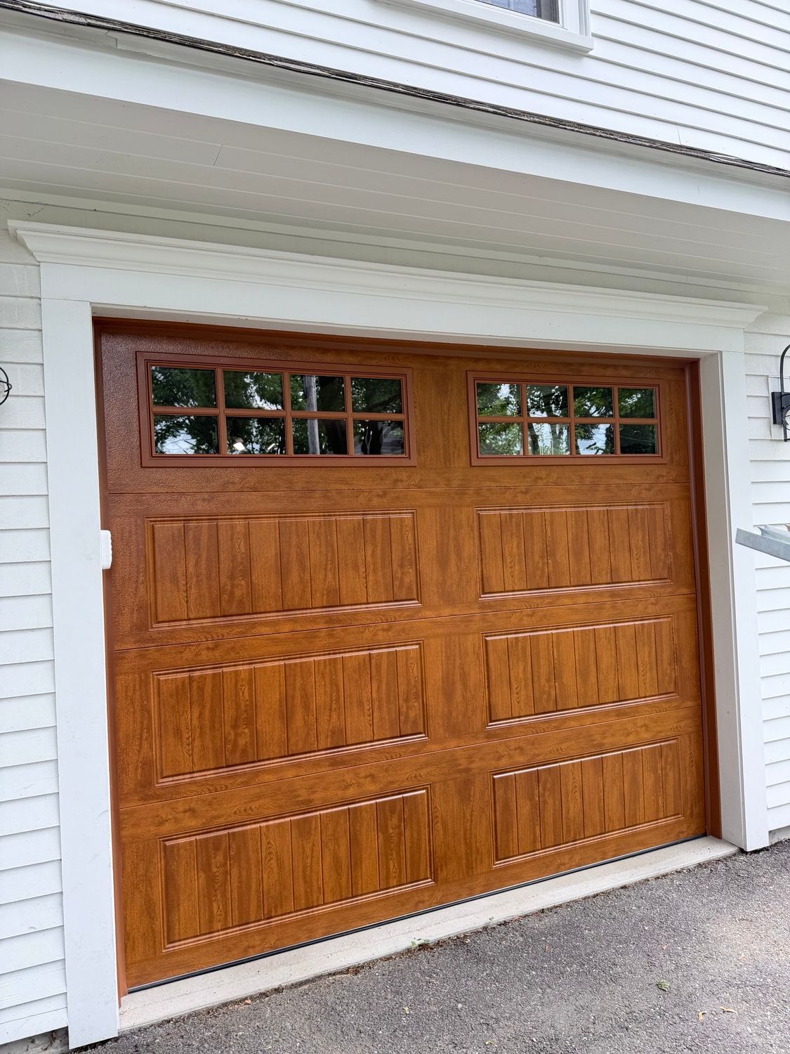 Wooden garage door with small window panes on a white house exterior