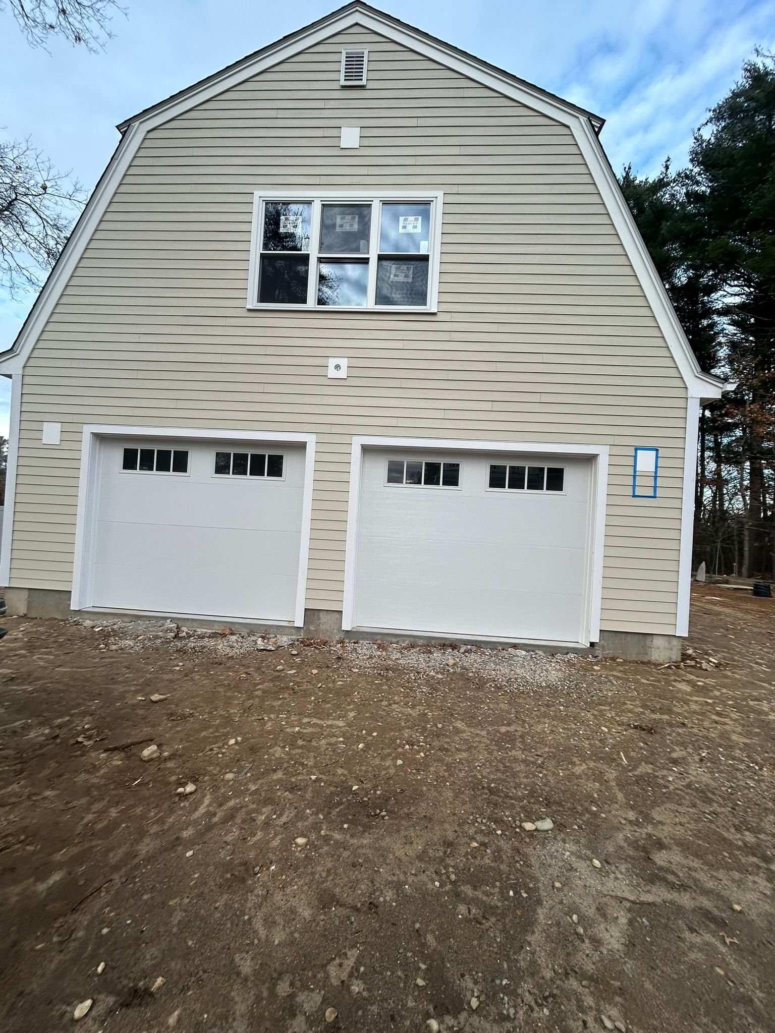 New beige house with two white garage doors and a small front window under construction