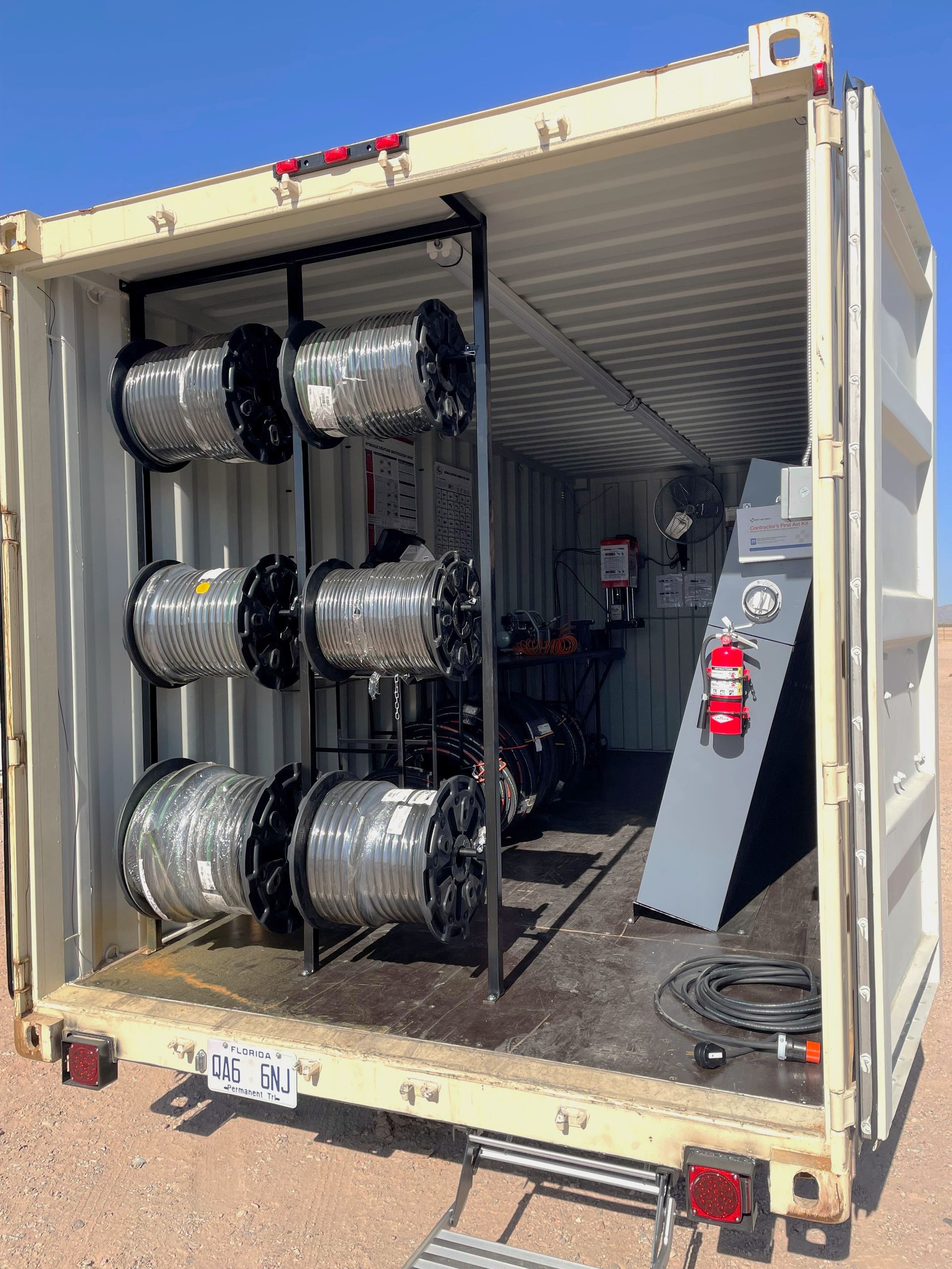 A shipping container filled with rolls of wire and a ladder.