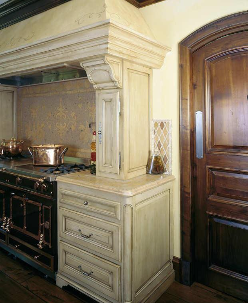 Cream-colored kitchen cabinets with range hood and a dark wooden door.