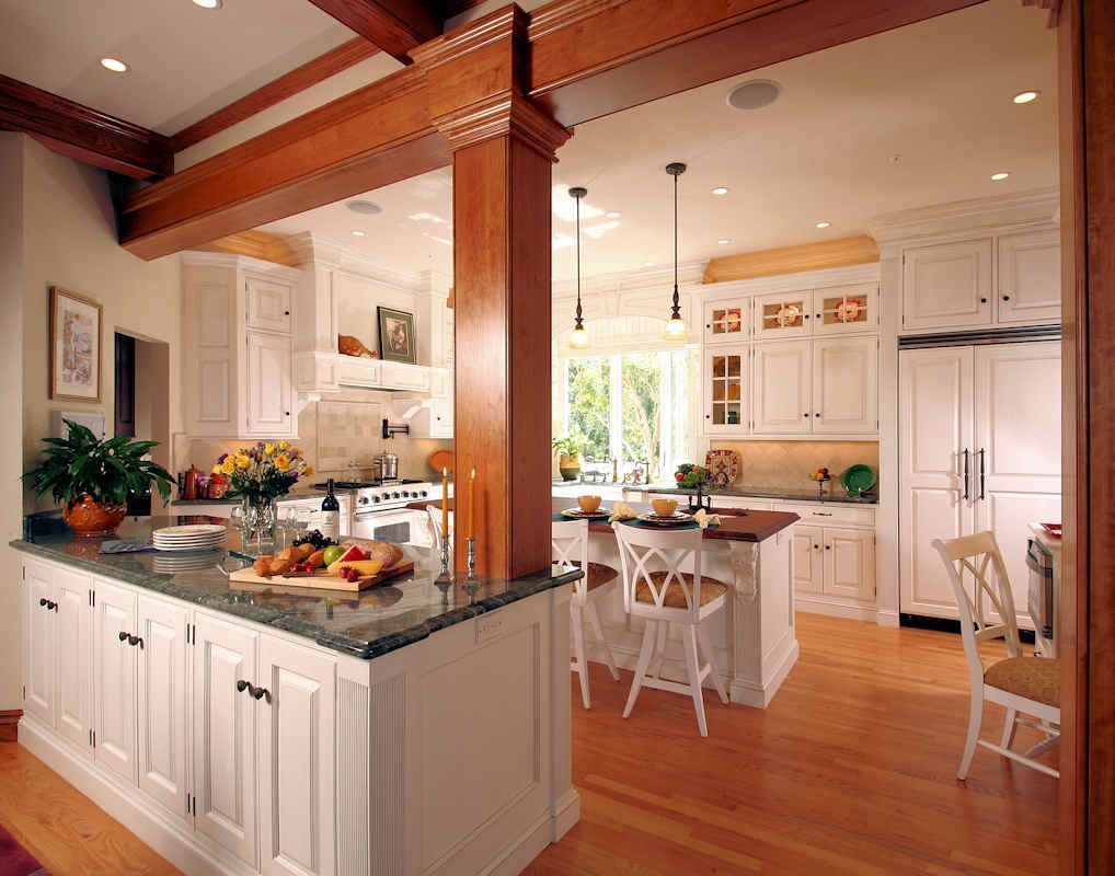 Bright kitchen with white cabinets, wood beams, and island with granite countertop.