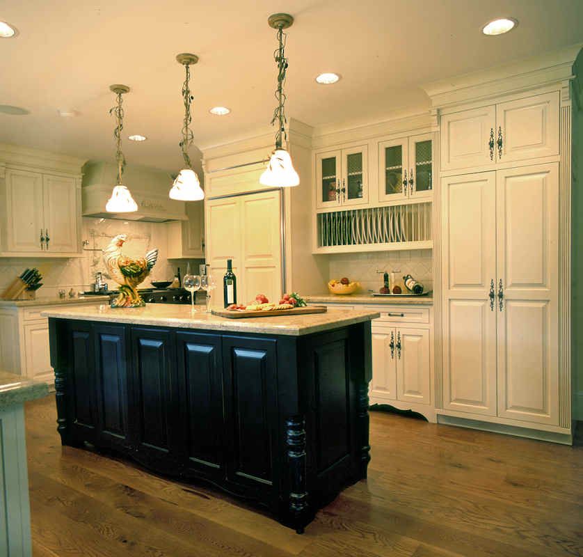 Kitchen with a dark island, white cabinets, and pendant lights.