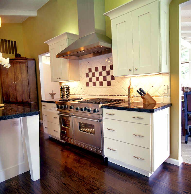 Kitchen with cream cabinets, stainless steel appliances, and checkerboard backsplash.