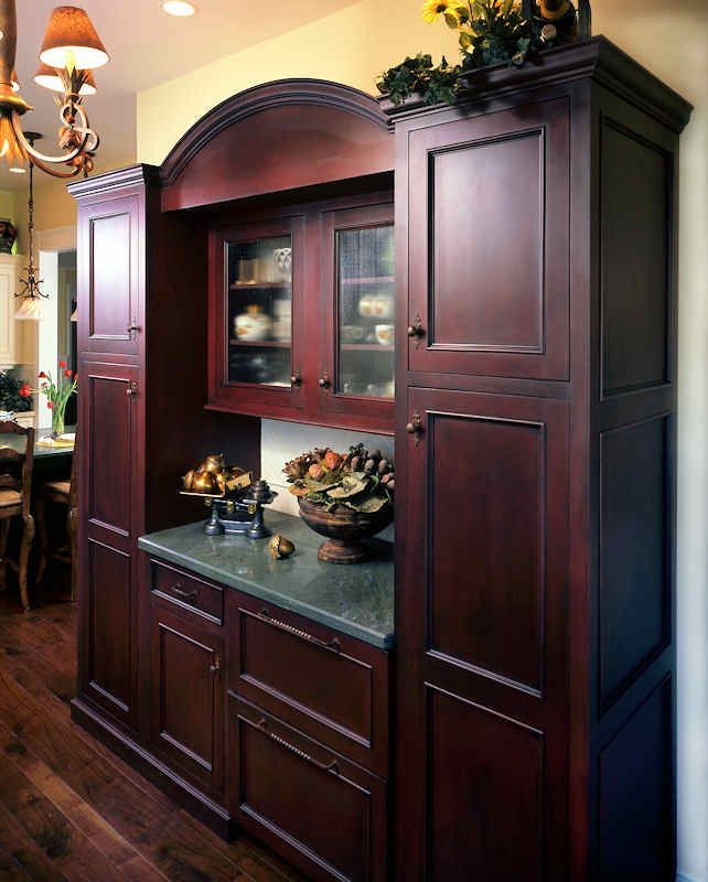 Dark wood kitchen cabinet with a green countertop and glass-front display cabinet.