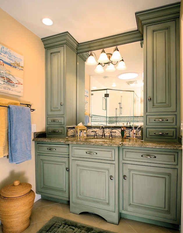 Bathroom vanity with sage green cabinets, granite countertop, and large mirror.