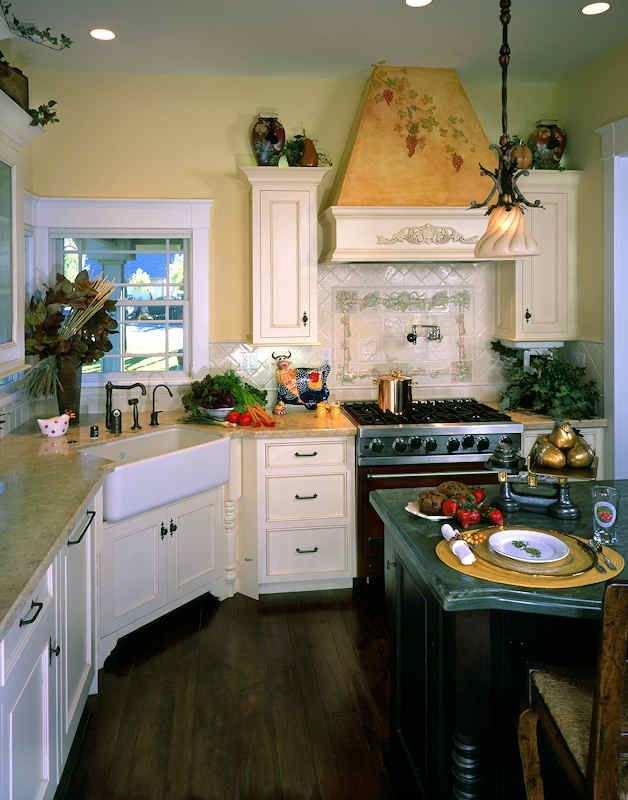 Cream-colored kitchen with a farmhouse sink, range, and hood; dark wood floor, light countertops.