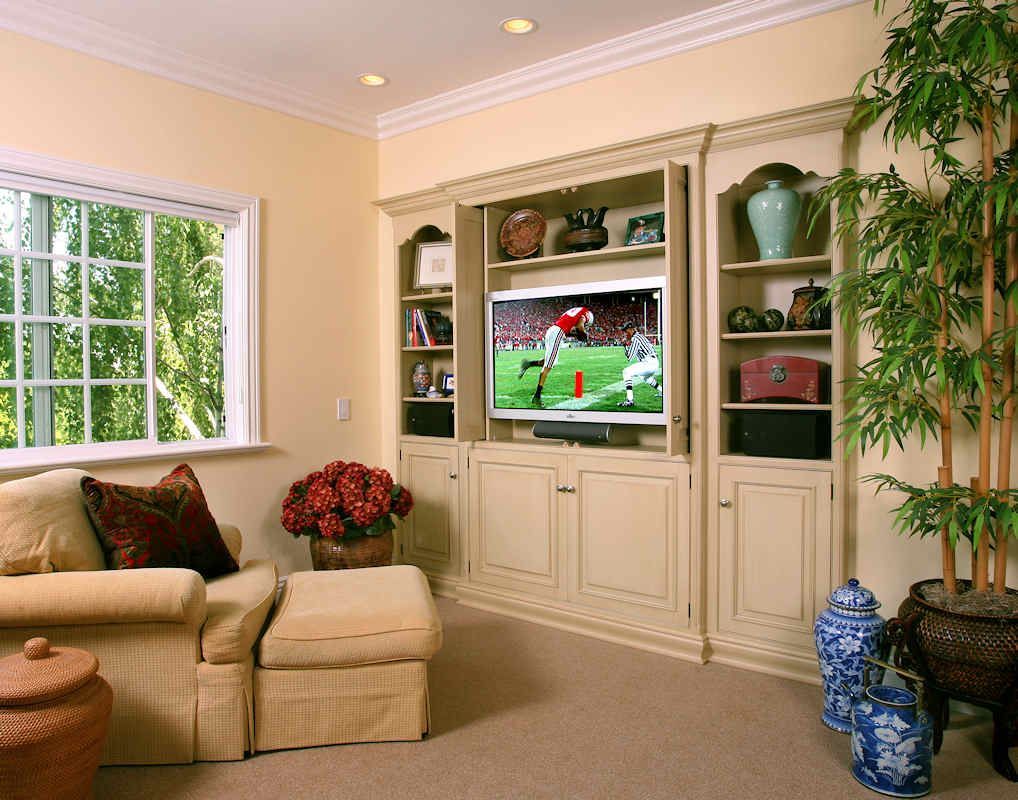 Cozy living room with built-in TV cabinet, window, and armchair. Light color scheme.