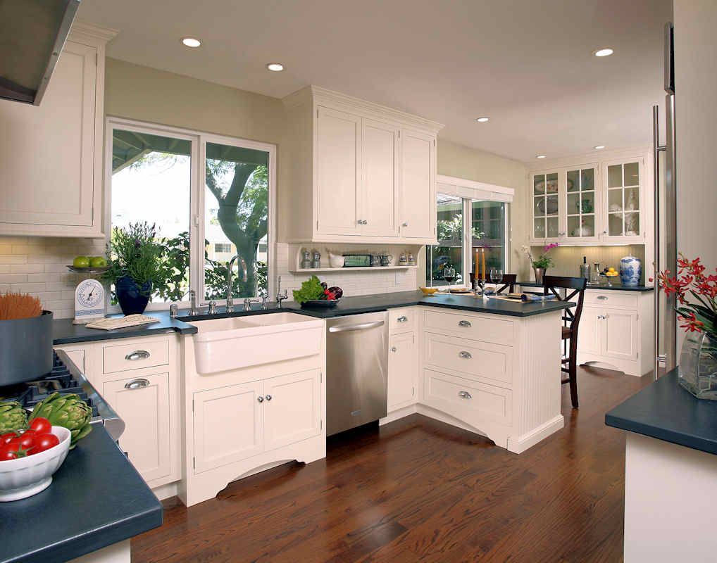 White kitchen with dark countertops, stainless steel appliances, and dark hardwood floors.