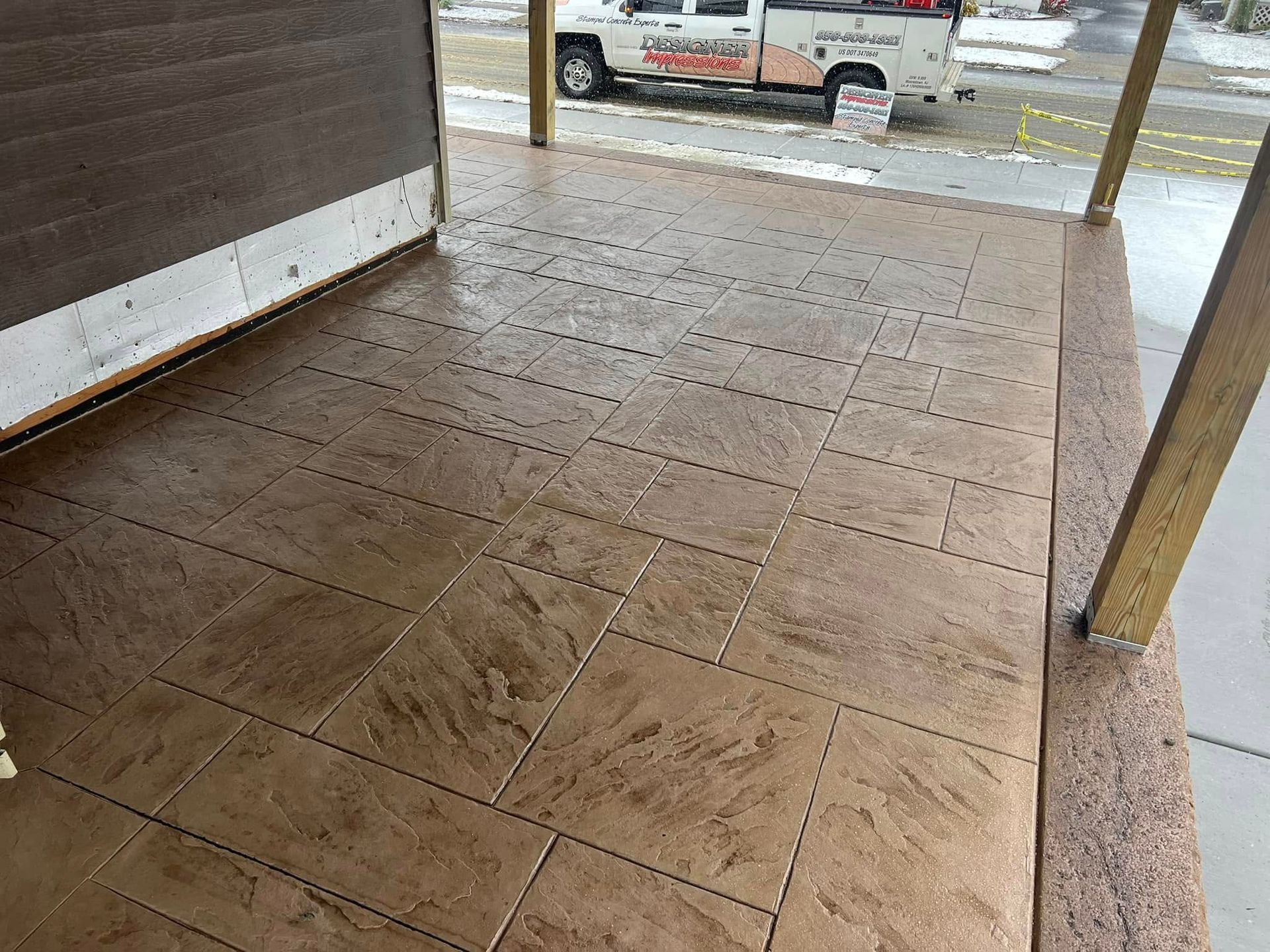 Brown tiled porch with a truck parked in the background.