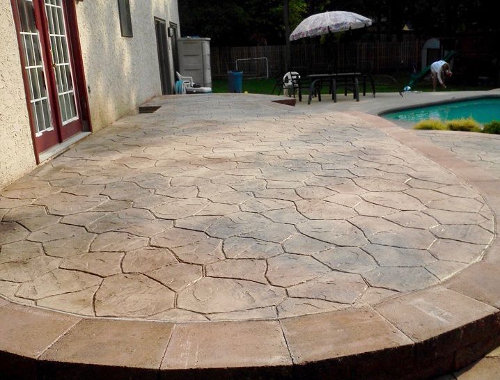 Stamped concrete patio with stone pattern, next to a house and swimming pool.