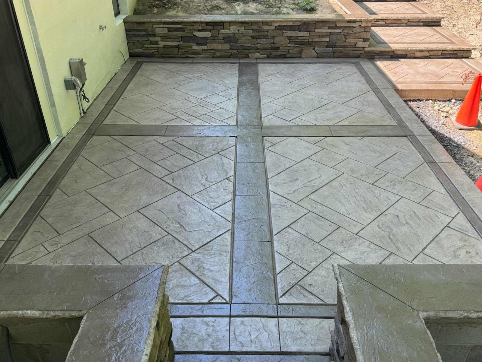 Decorative concrete patio with textured gray patterns and stone accents.
