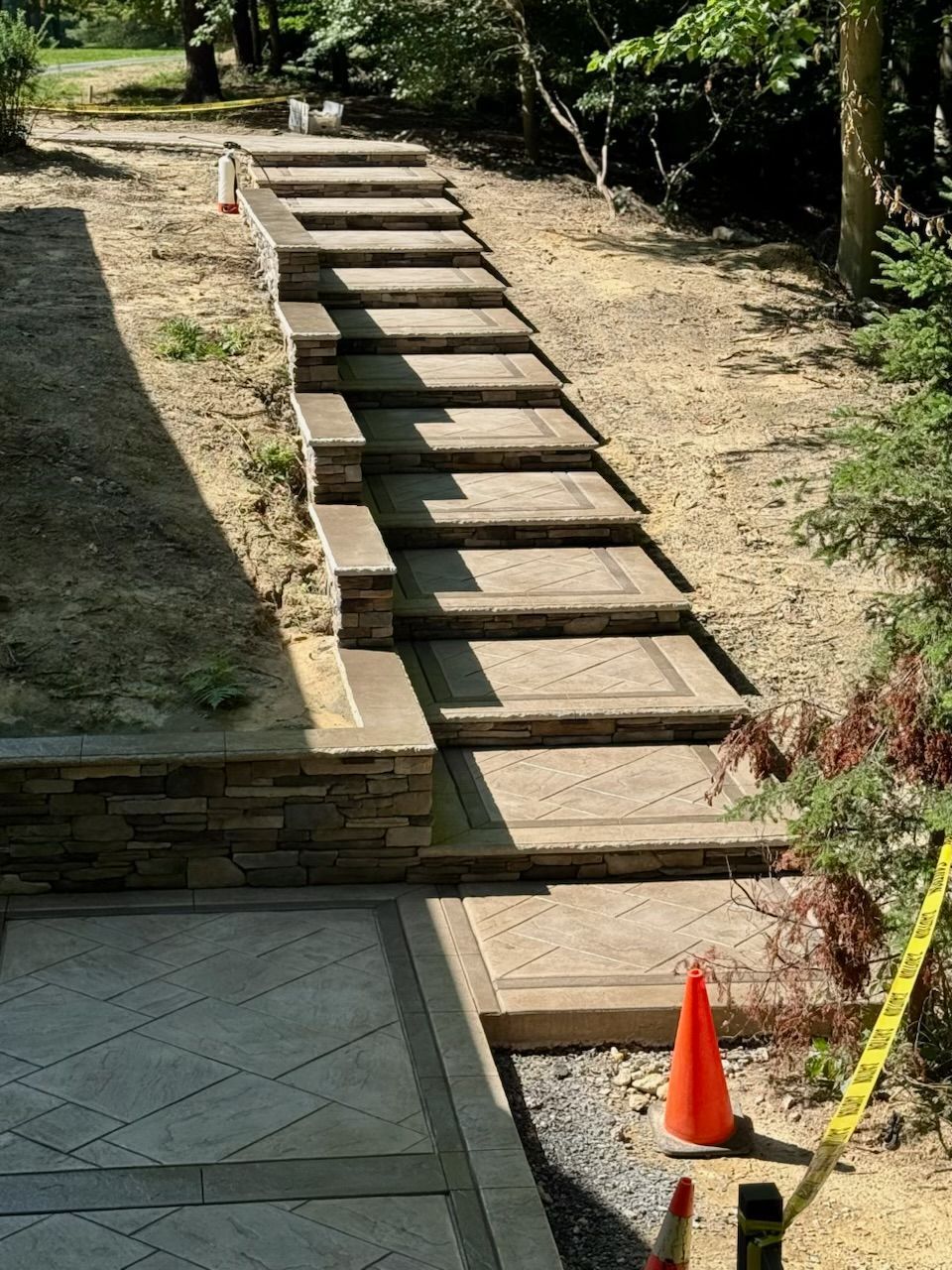 Stone steps ascend a hillside pathway, bordered by a low stone wall and dirt.