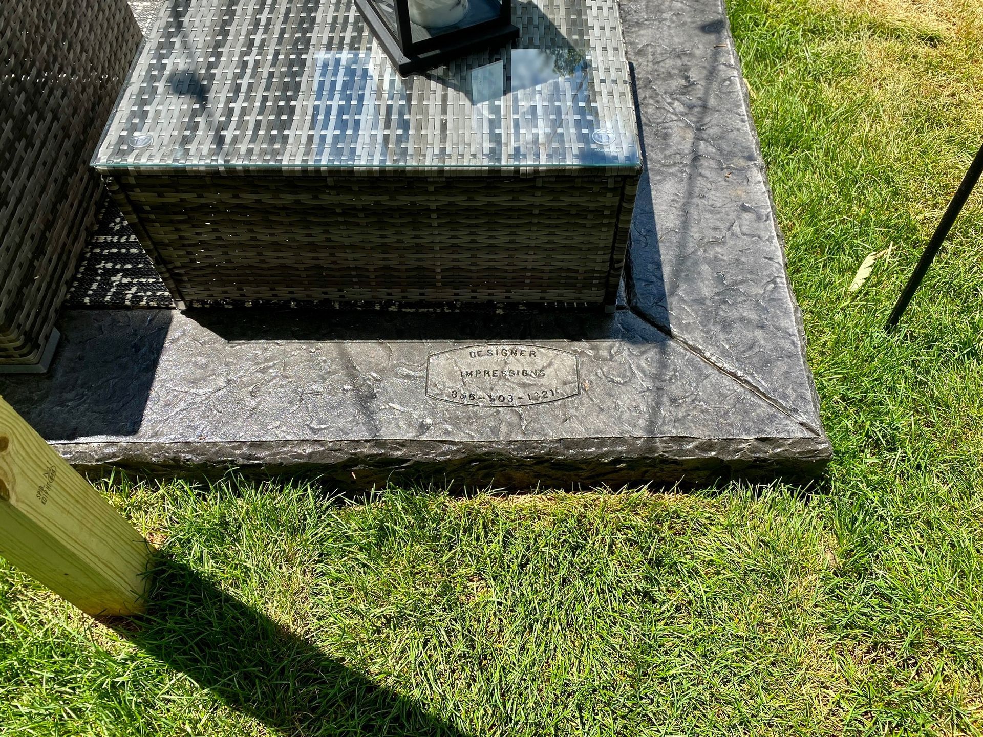 Close-up of a dark gray stone memorial with a glass-topped structure on top, in a grassy area.