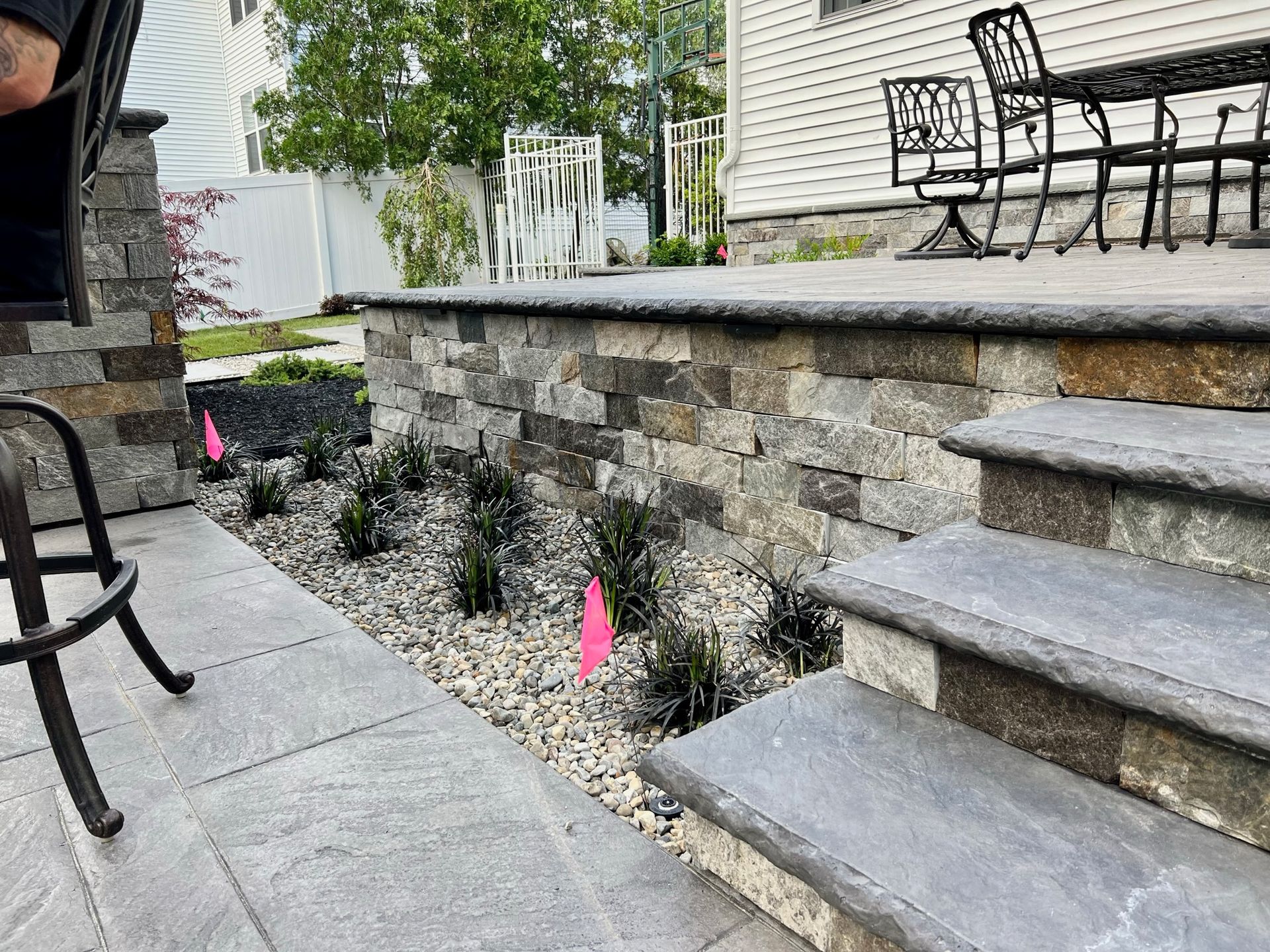 Stone patio with retaining wall, steps, and landscaping.