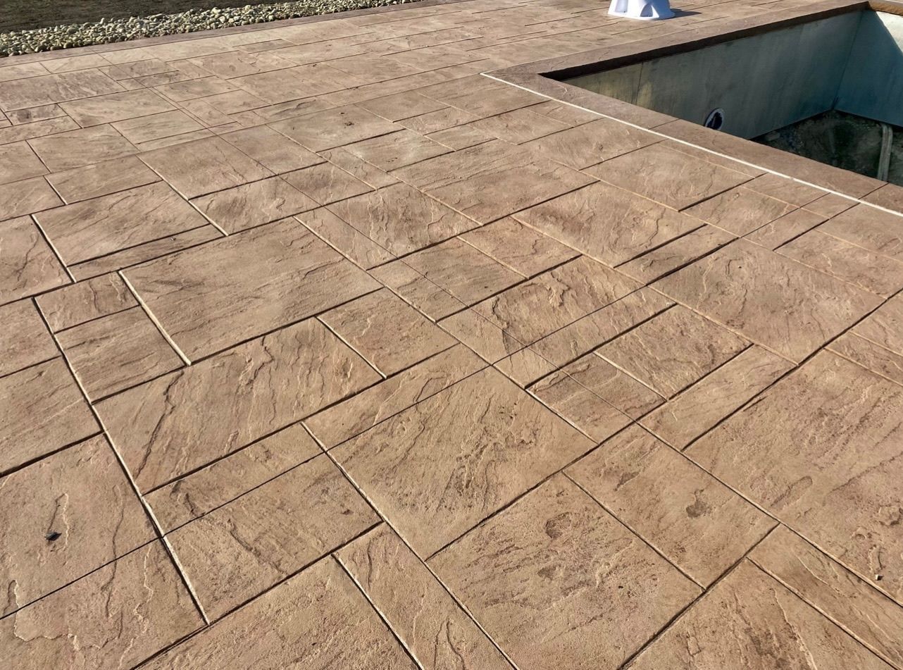 Tan stamped concrete patio with rectangular stone pattern.