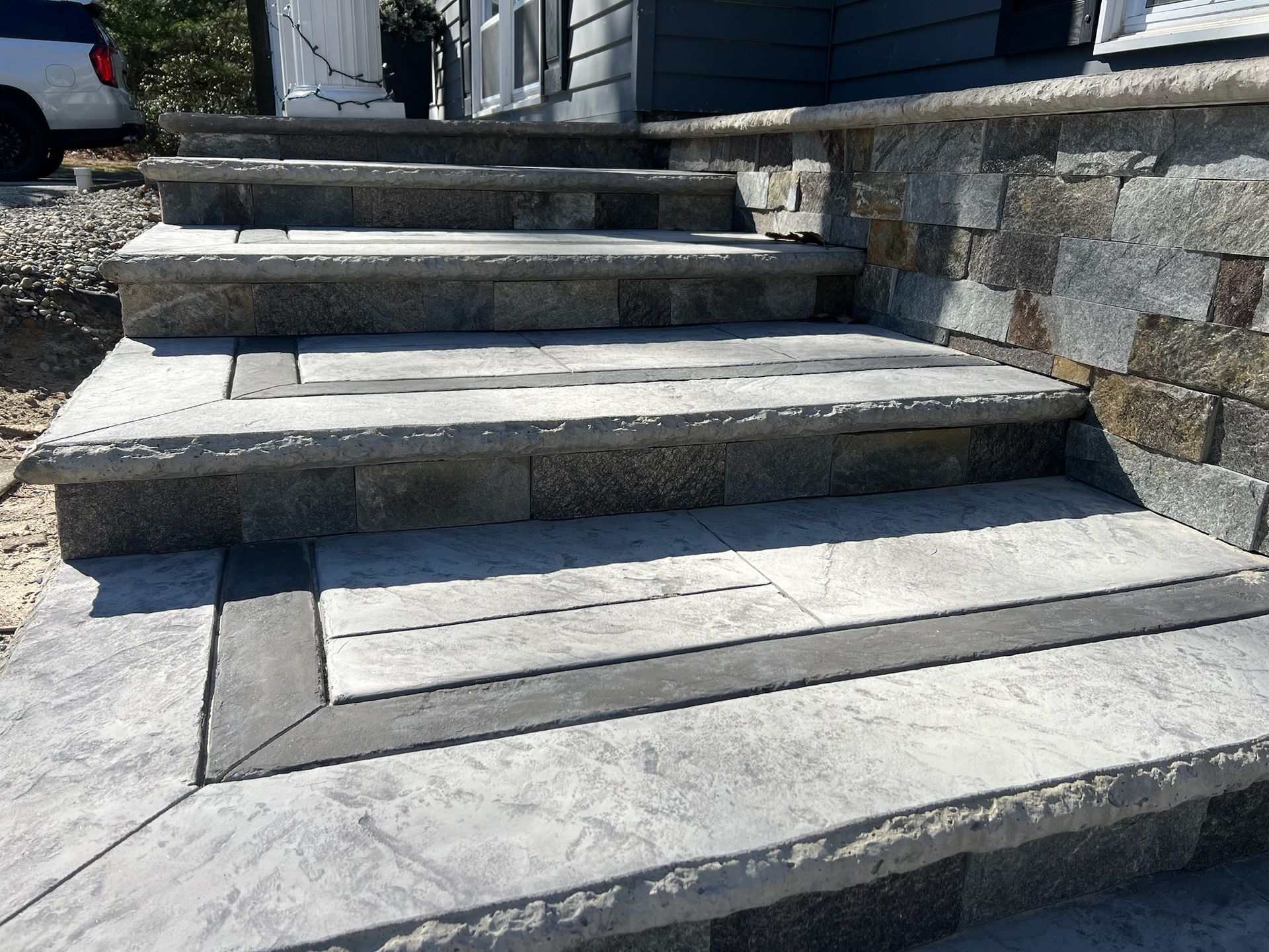 Stone steps leading up to a house, featuring a textured surface and contrasting borders.