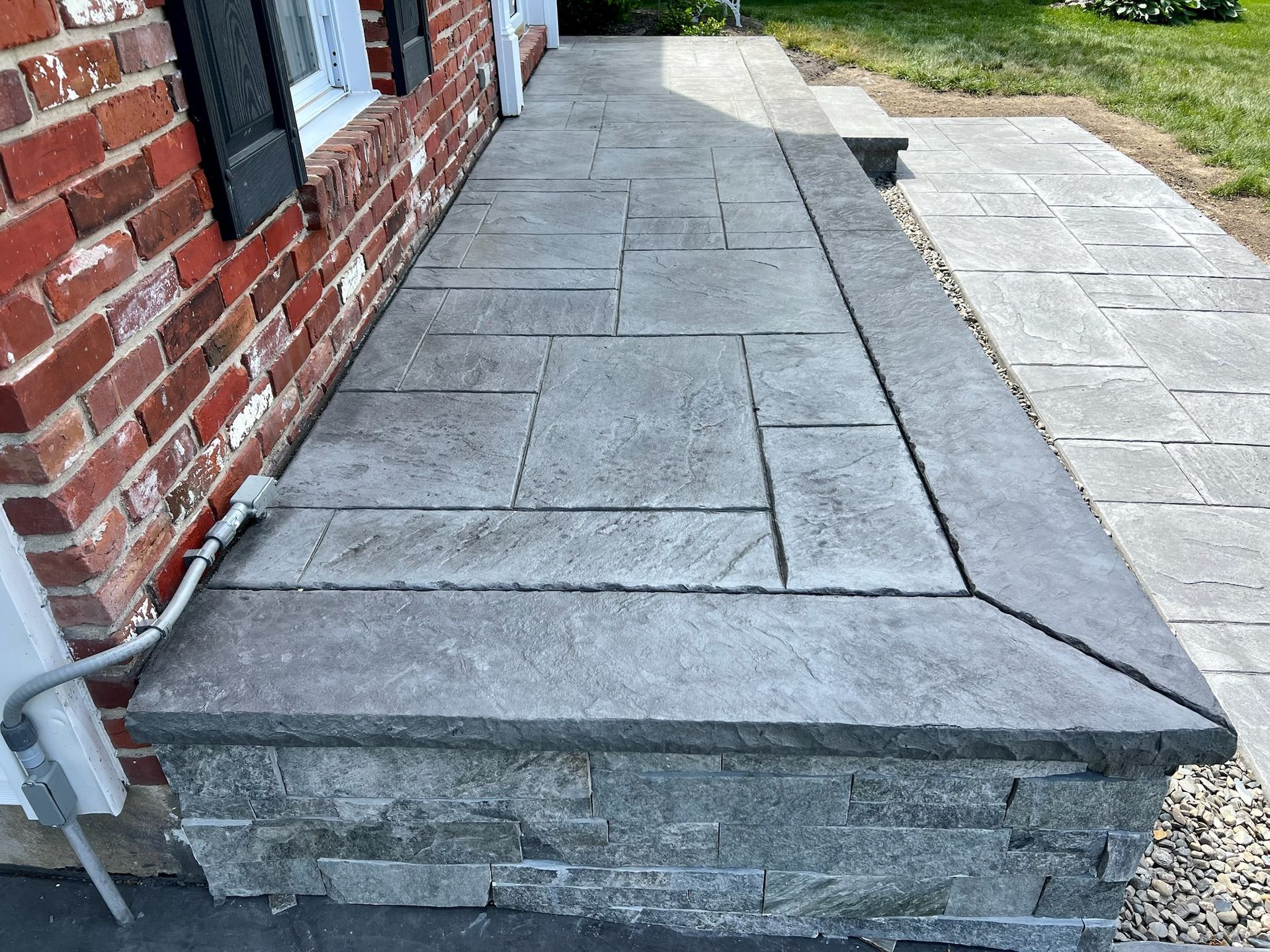 Stone front porch with brick home and paved walkway.