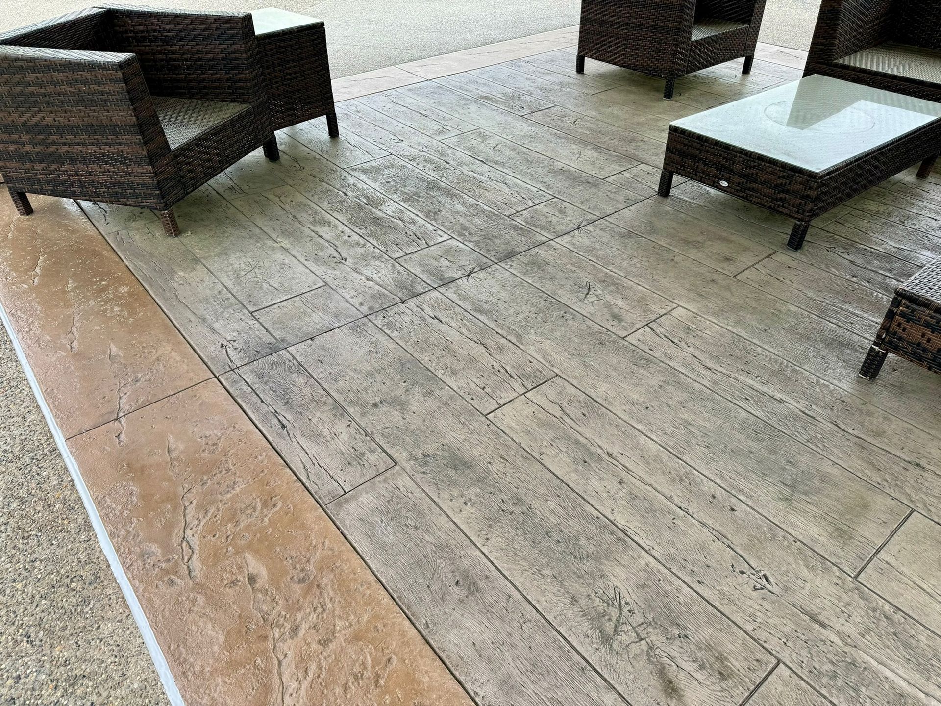 Outdoor patio with wicker furniture on stamped concrete with a wood-grain pattern.