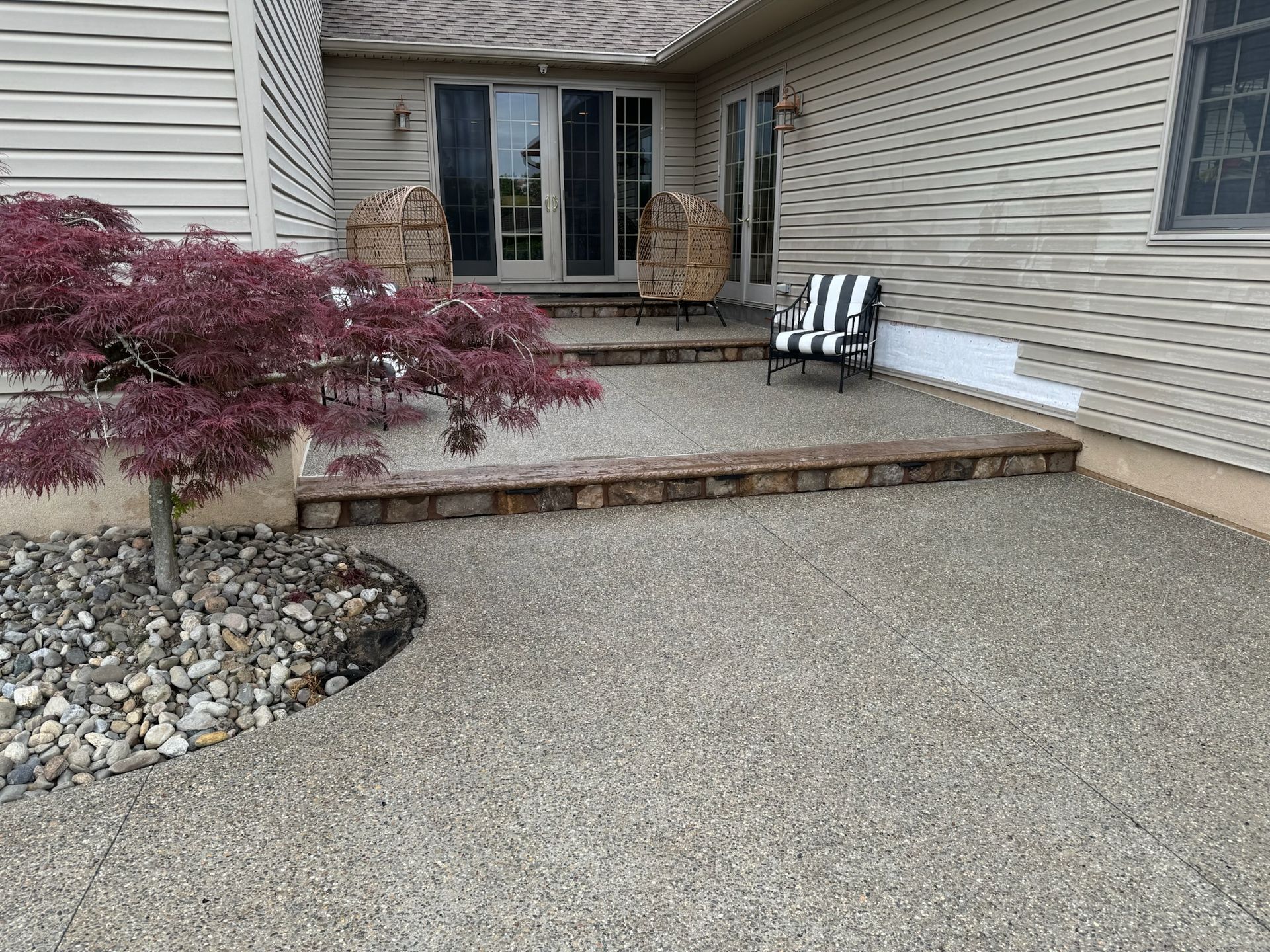 A patio with steps and seating. A red tree is on the left. Exterior of a building.