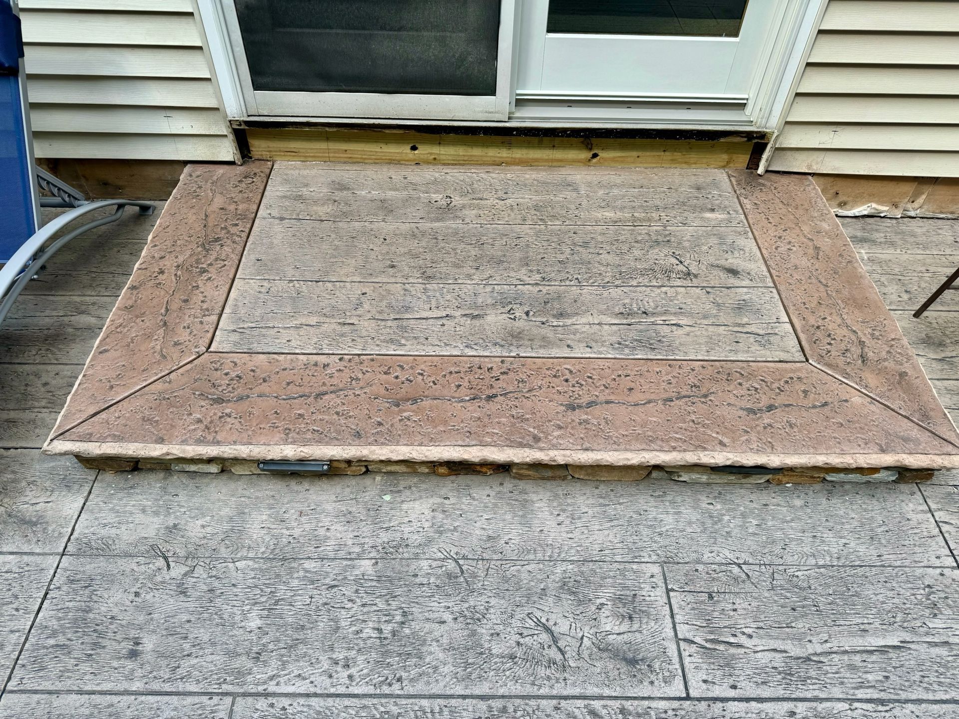 Concrete step with brown border in front of a sliding door.